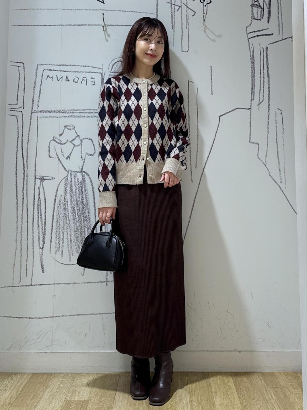 ベージュ系のカーディガン/ボレロ、ブラウン系のブーツ、ブラック系のショルダーバッグを着用したレディースの秋コーディネートの1枚目の写真
