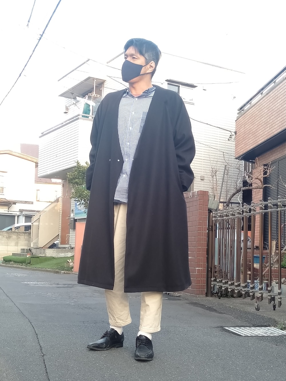 ブラック系のドレスシューズ、ブルー系のシャツ/ブラウス、ブラック系のノーカラーコートを着用したメンズの春コーディネートの2枚目の写真