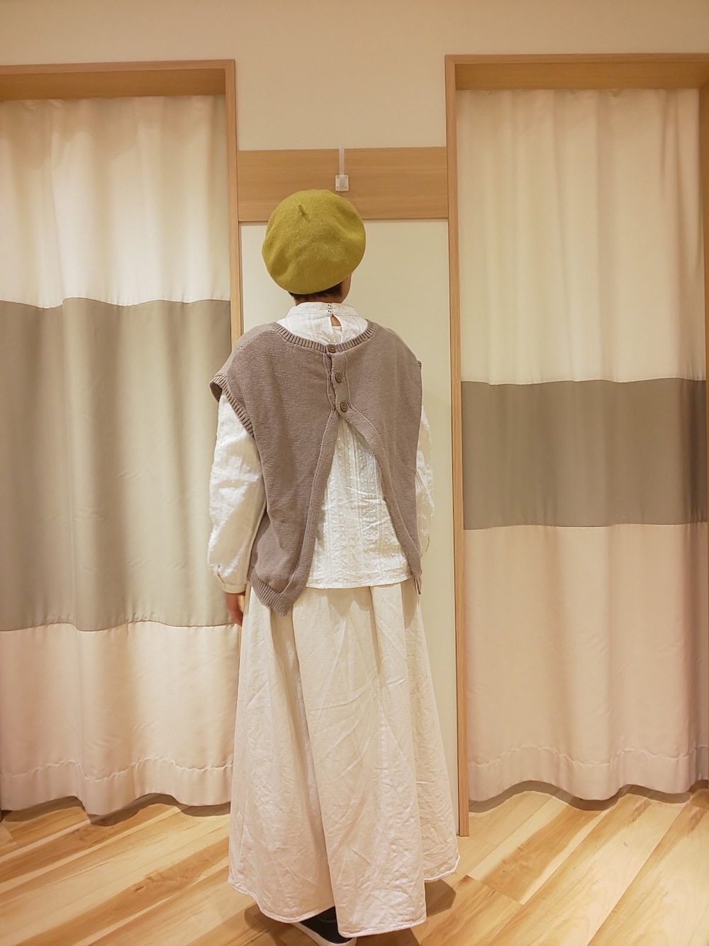 ホワイト系のスカート、ベージュ系のベスト、ホワイト系のシャツ/ブラウスを着用したレディースの春コーディネートの2枚目の写真