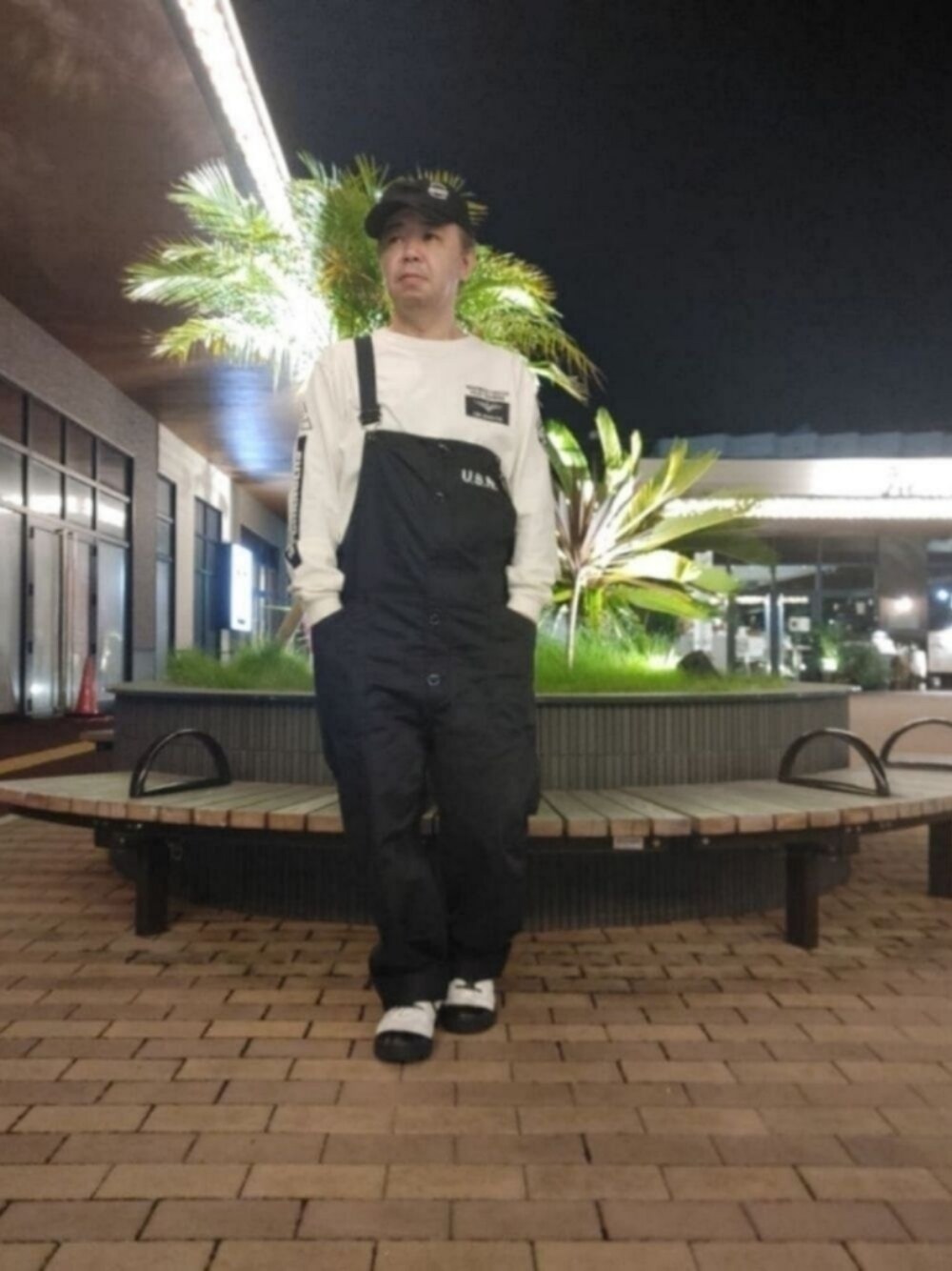 ホワイト系のスニーカー、ブルー系のサロペット/オーバーオール、ホワイト系のTシャツ/カットソーを着用したメンズの秋コーディネートの1枚目の写真