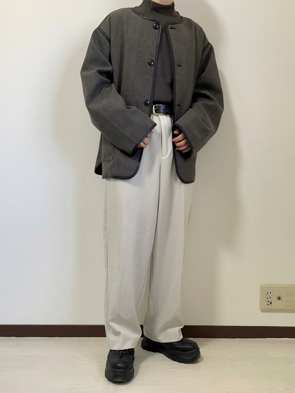 ベージュ系のスラックス、グレー系のノーカラージャケット、ブラック系のスニーカーを着用したメンズの秋コーディネートの1枚目の写真