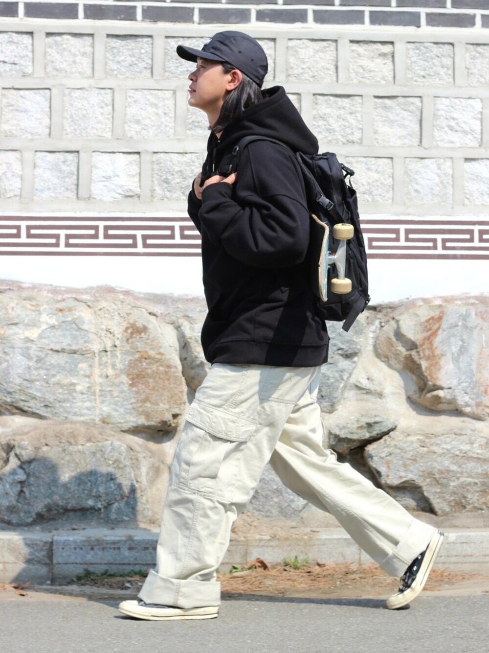 ブラック系のパーカー、ベージュ系のデニムパンツを着用したメンズの春コーディネートの3枚目の写真