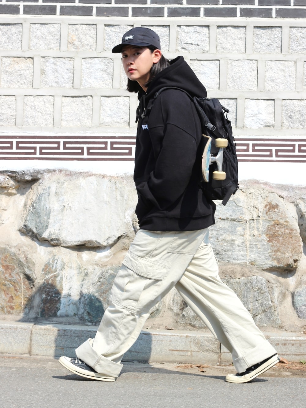 ブラック系のパーカー、ベージュ系のデニムパンツを着用したメンズの春コーディネートの2枚目の写真