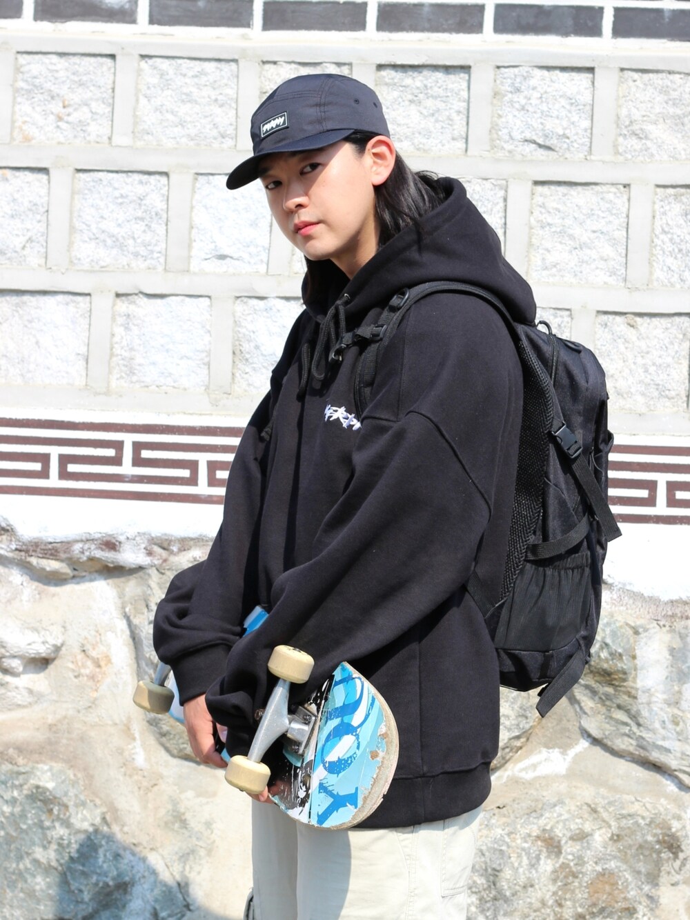 ブラック系のパーカー、ベージュ系のデニムパンツを着用したメンズの春コーディネートの4枚目の写真