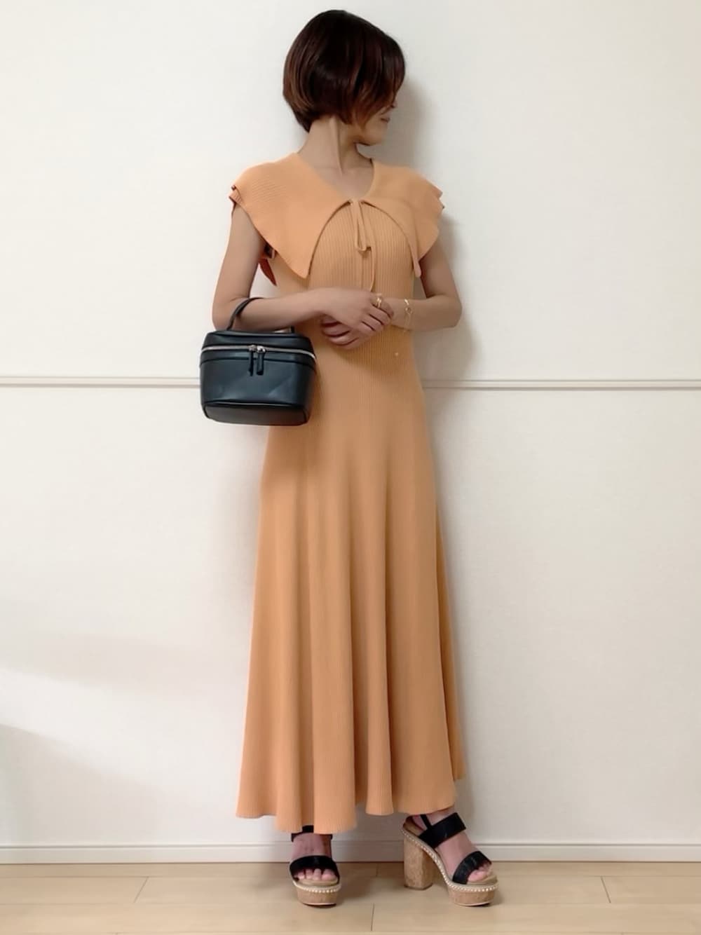 オレンジ系のワンピース、ブラック系のサンダル、ブラック系のハンドバッグを着用したレディースの夏コーディネートの1枚目の写真