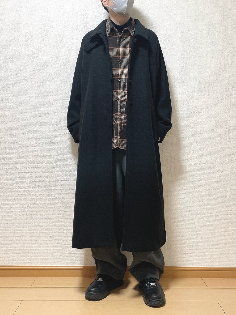 ブラック系のステンカラーコート、ブラウン系のシャツ/ブラウス、ブラック系のTシャツ/カットソーを着用したメンズの冬コーディネートの1枚目の写真