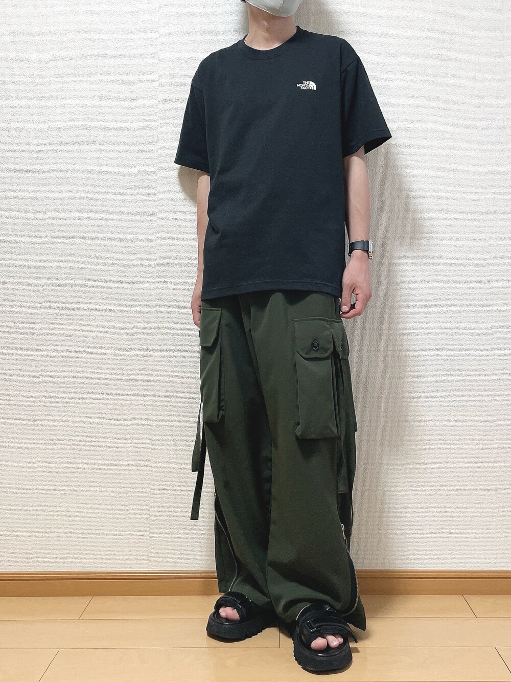 ブラック系のTシャツ/カットソー、グリーン系のカーゴパンツ、ブラック系のサンダルを着用したメンズの春コーディネートの1枚目の写真