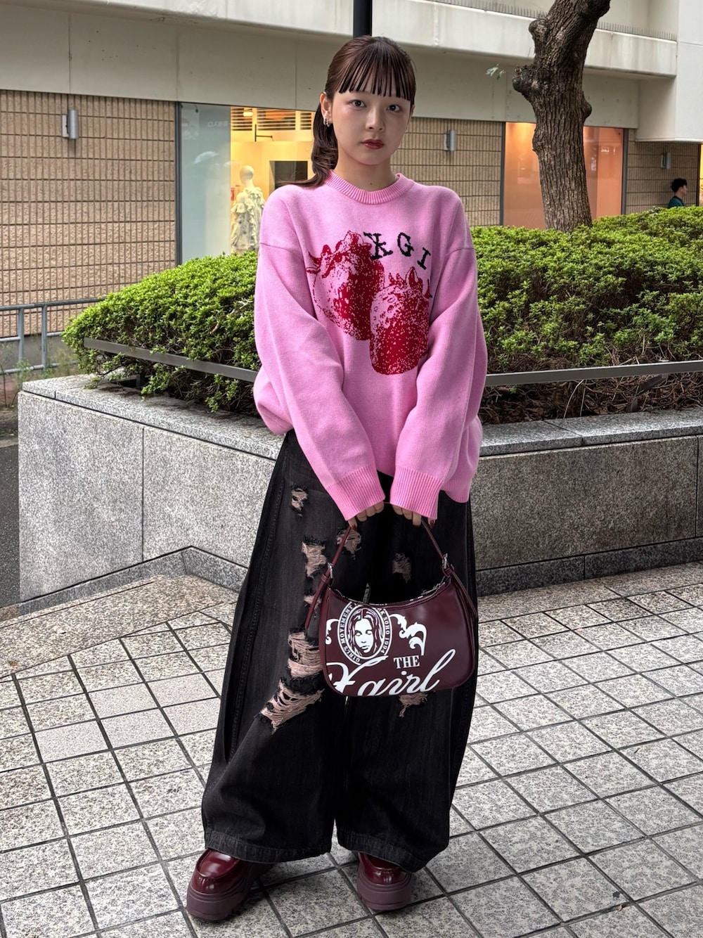 ピンク系のニット/セーター、ブラック系のデニムパンツ、レッド系のハンドバッグを着用したレディースの秋コーディネートの1枚目の写真