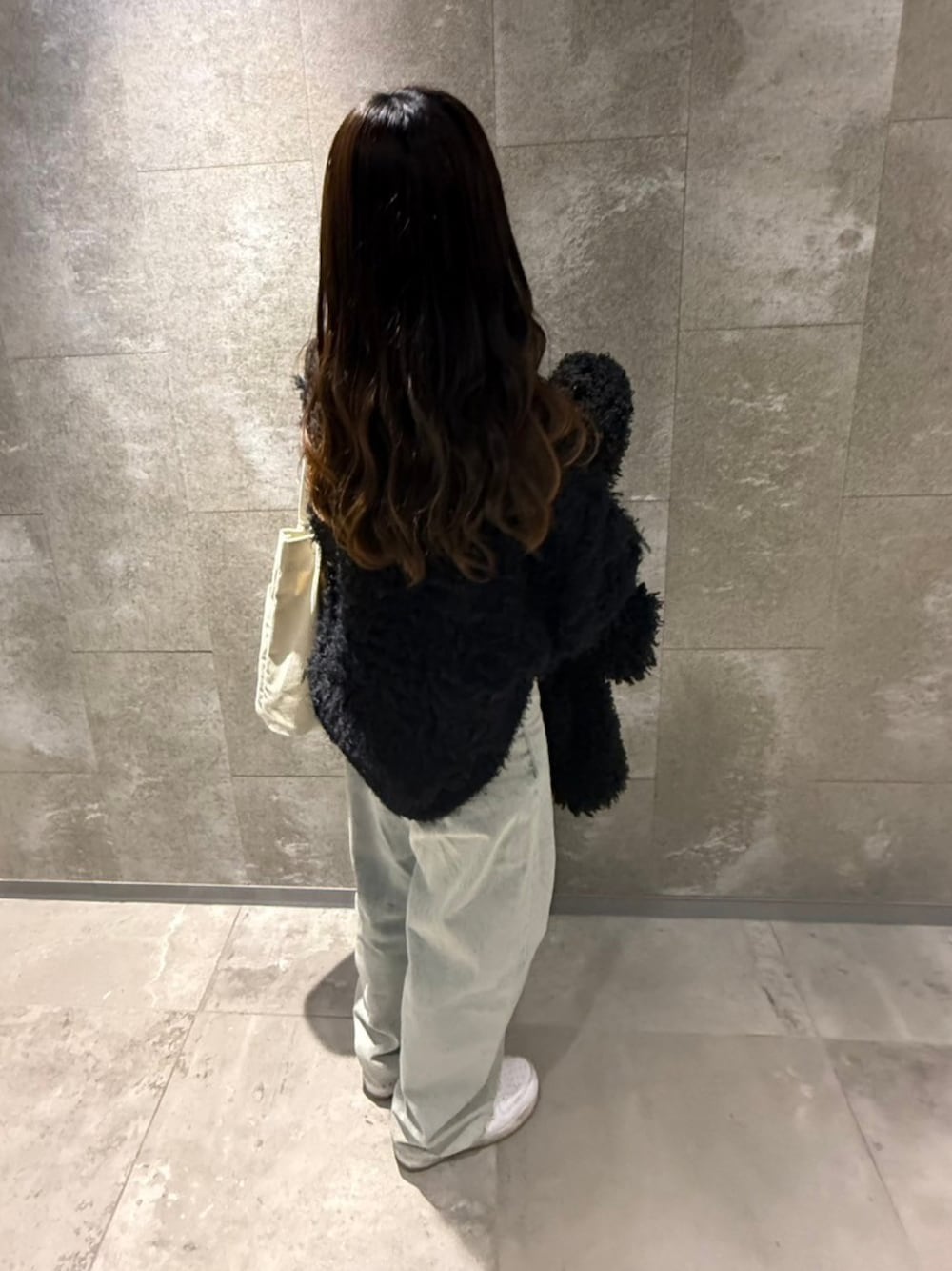 ブラック系のニット/セーター、ホワイト系のスニーカー、ホワイト系のトートバッグを着用したレディースの春コーディネートの1枚目の写真