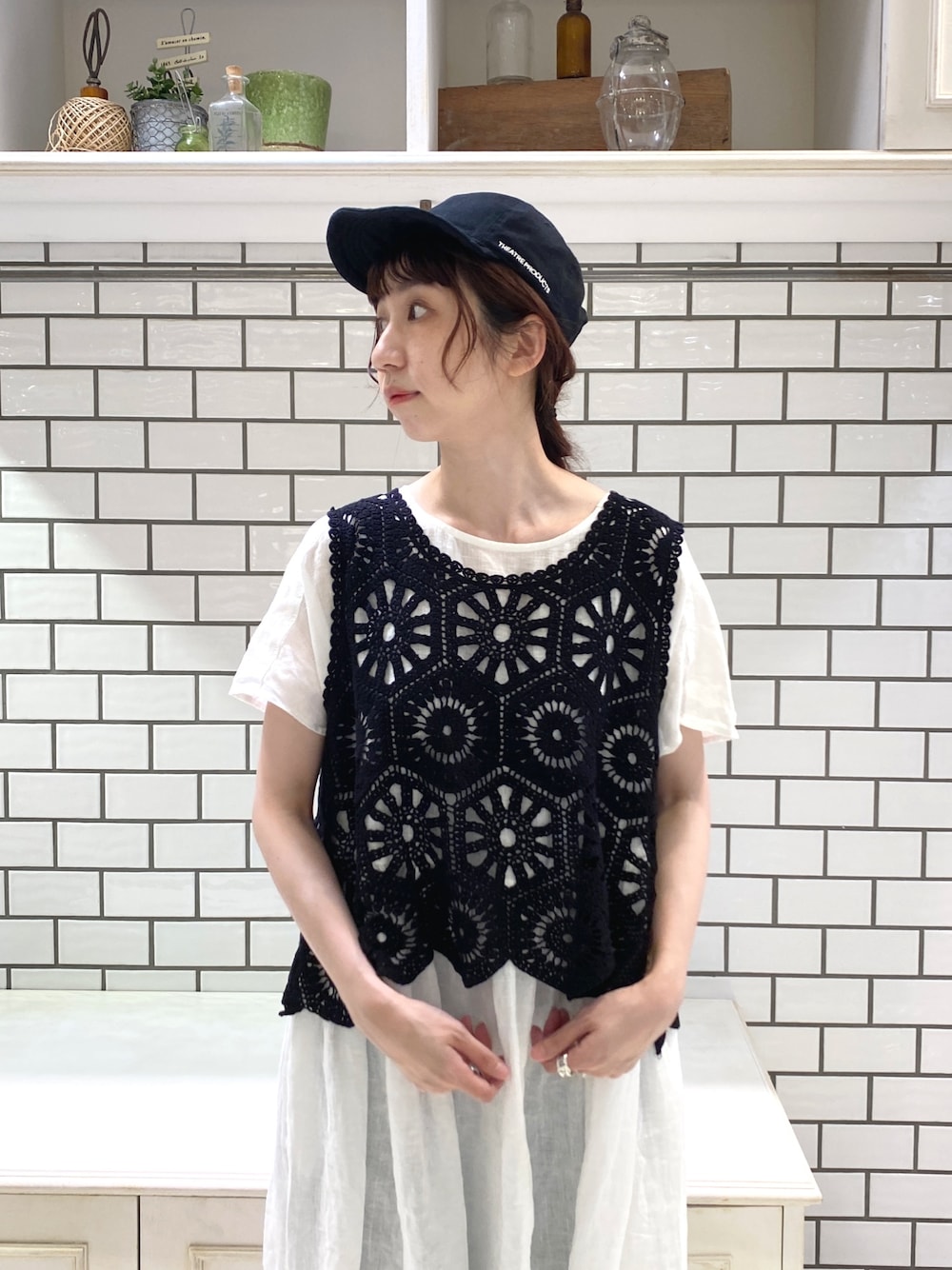 ブラック系のベスト、ホワイト系のワンピース、ブルー系のデニムパンツを着用したレディースの夏コーディネートの3枚目の写真