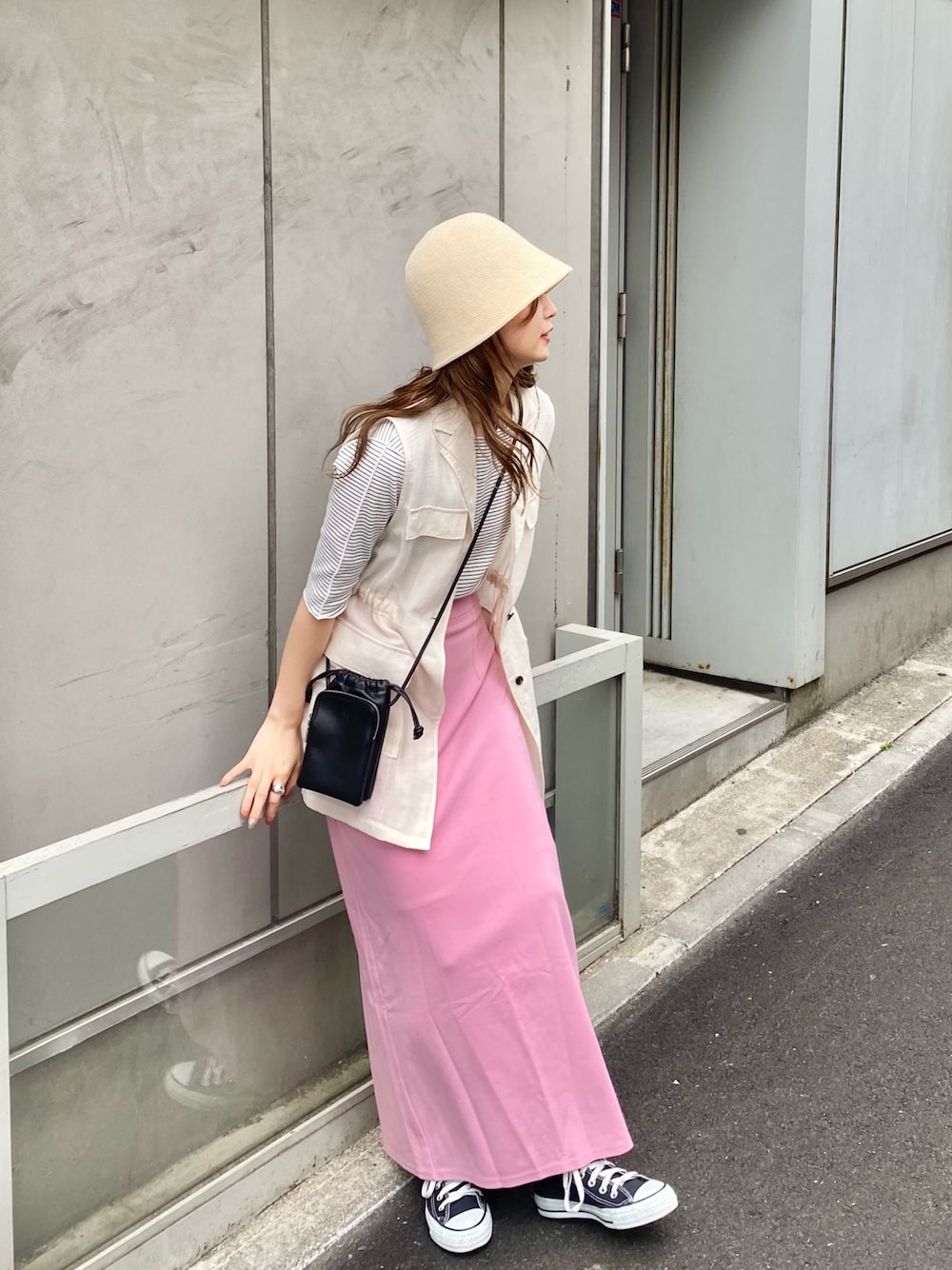 ピンク系のスカート、ホワイト系のベスト、ホワイト系のTシャツ/カットソーを着用したレディースの春コーディネートの1枚目の写真