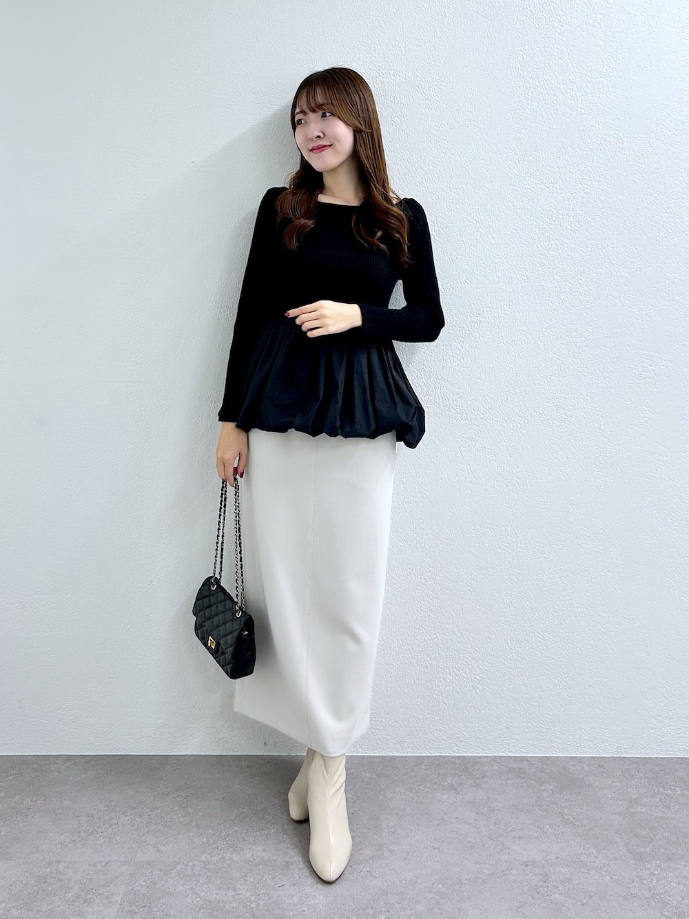 ブラック系のニット/セーター、グレー系のスカートを着用したレディースの秋コーディネートの1枚目の写真