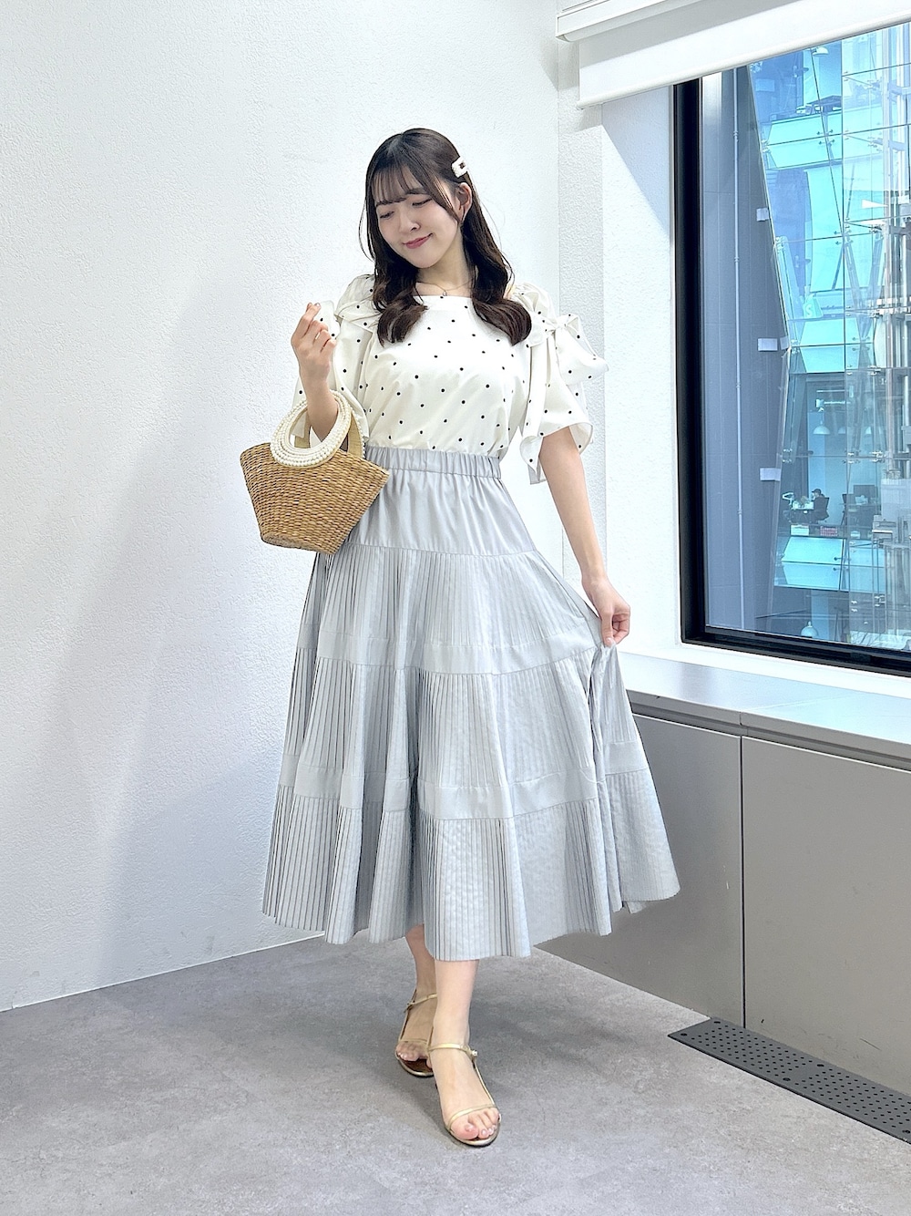 ホワイト系のシャツ/ブラウス、グレー系のスカート、ベージュ系のかごバッグを着用したレディースの冬コーディネートの1枚目の写真