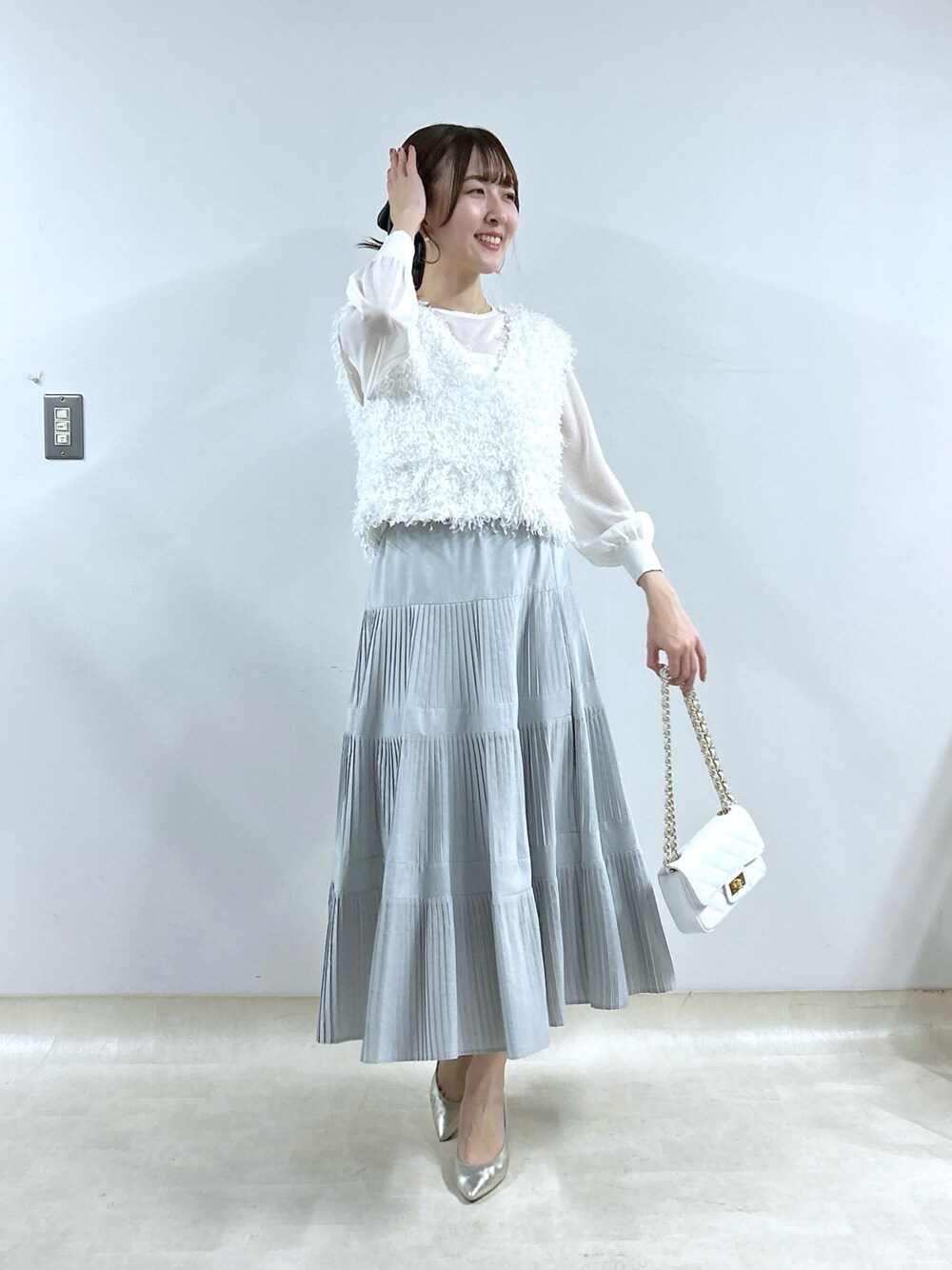 ホワイト系のシャツ/ブラウス、グレー系のスカート、ホワイト系のニット/セーターを着用したレディースの冬コーディネートの1枚目の写真