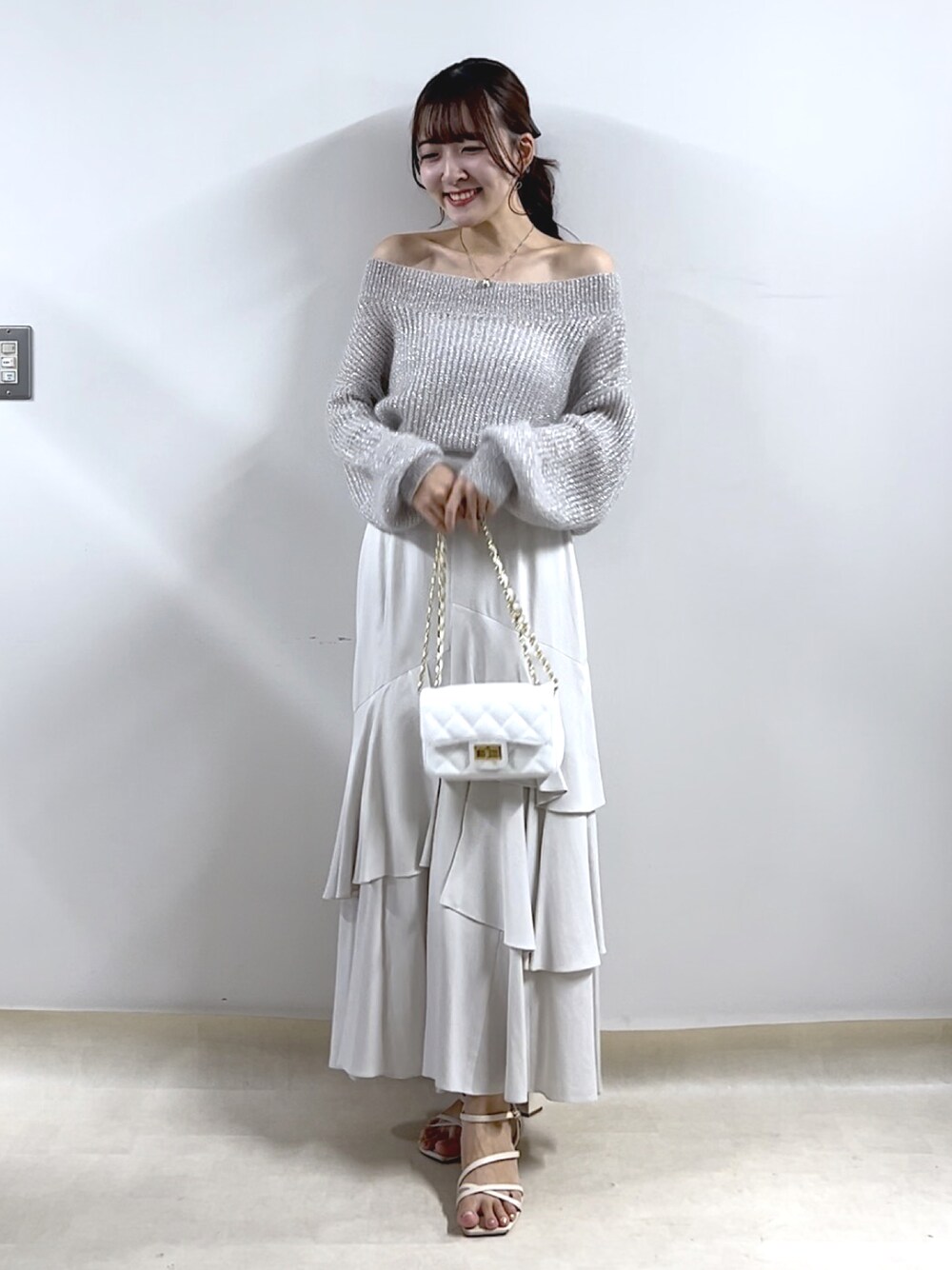 シルバー系のニット/セーター、グレー系のスカートを着用したレディースの秋コーディネートの1枚目の写真