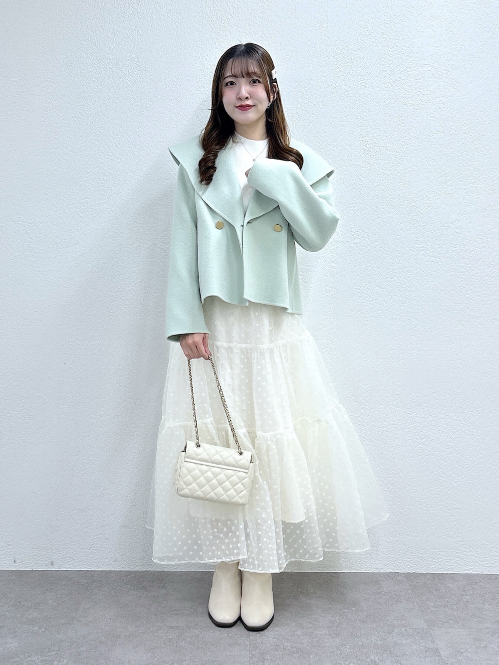 グリーン系のその他アウター、ホワイト系のニット/セーター、ホワイト系のスカートを着用したレディースの秋コーディネートの1枚目の写真