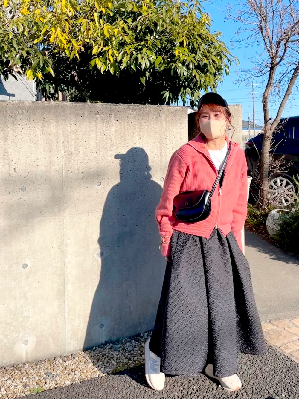 ブラック系のワンピース、ピンク系のニット/セーター、ホワイト系のTシャツ/カットソーを着用したレディースの春コーディネートの1枚目の写真
