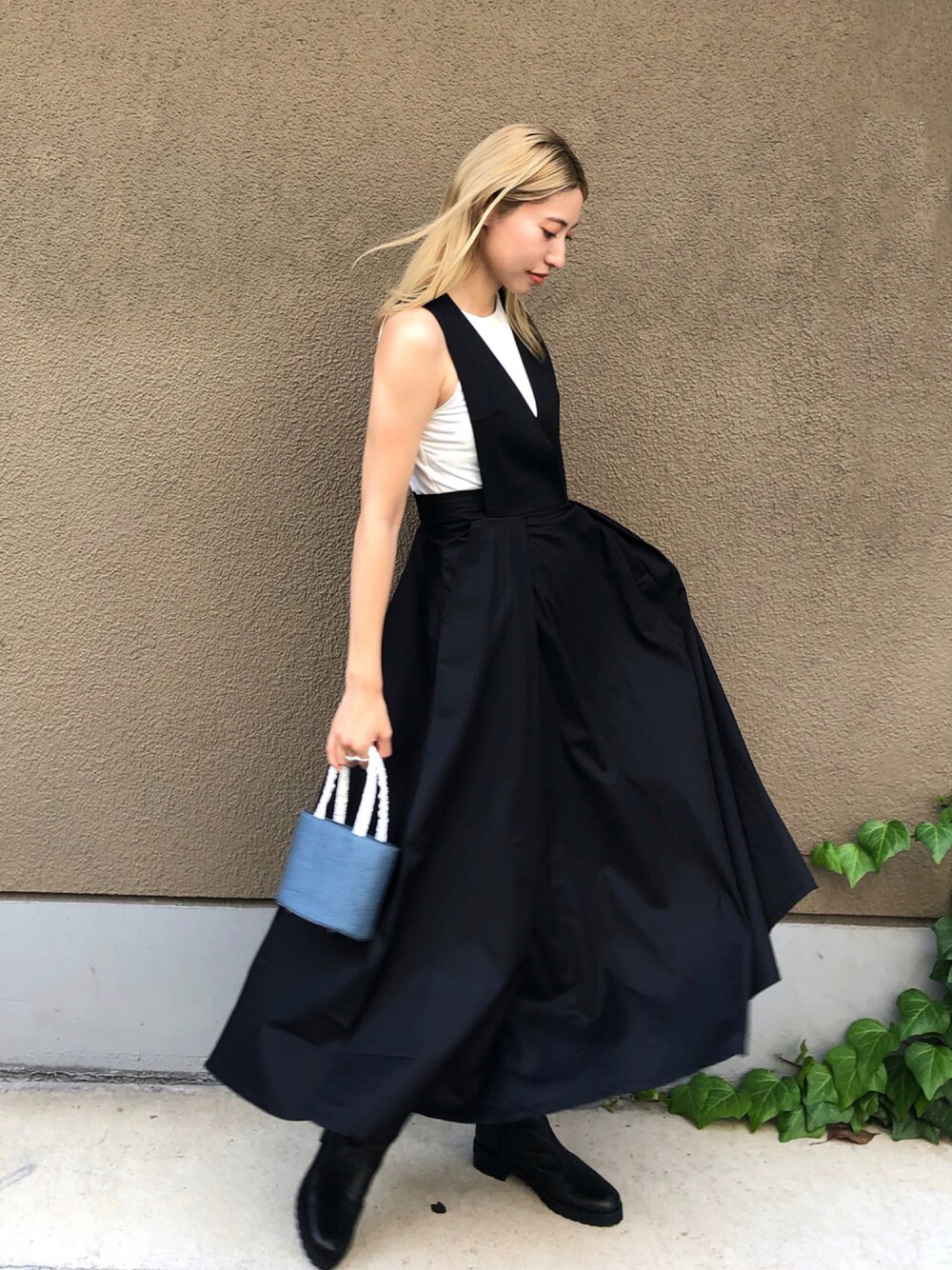 ブラック系のワンピース/ドレス、ブルー系のハンドバッグ、ブラック系のブーツを着用したレディースの秋コーディネートの1枚目の写真