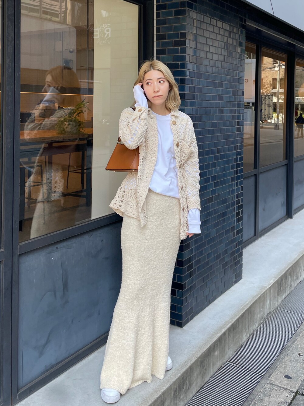 ホワイト系のスカート、ブラウン系のハンドバッグ、ホワイト系のスニーカーを着用したレディースの春コーディネートの1枚目の写真