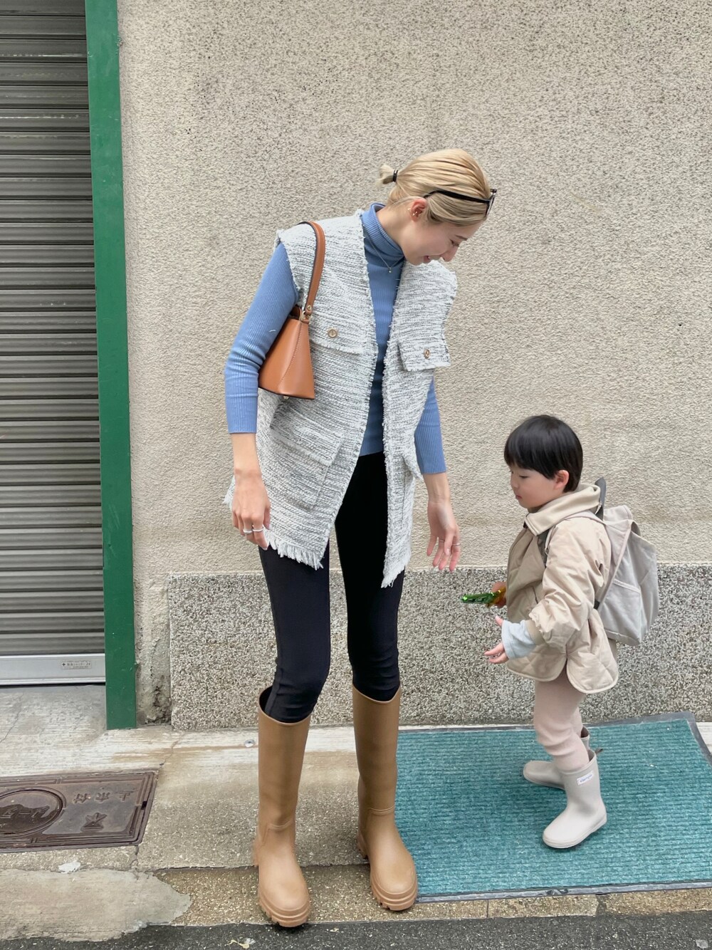 ブルー系のニット/セーター、ブラウン系のハンドバッグ、ホワイト系のベストを着用したレディースの春コーディネートの1枚目の写真