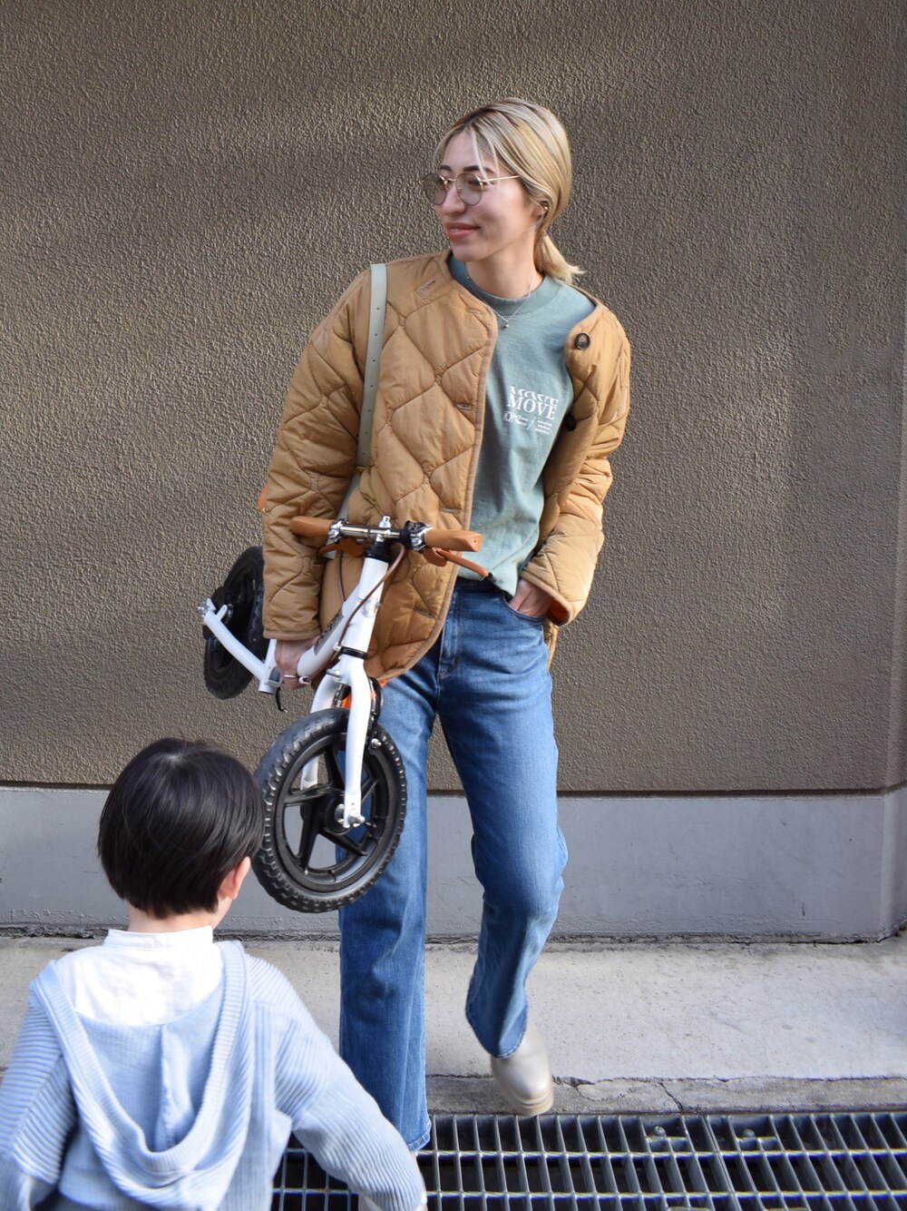 グリーン系のTシャツ/カットソー、ブルー系のデニムパンツ、ベージュ系のブーツを着用したレディースの春コーディネートの1枚目の写真