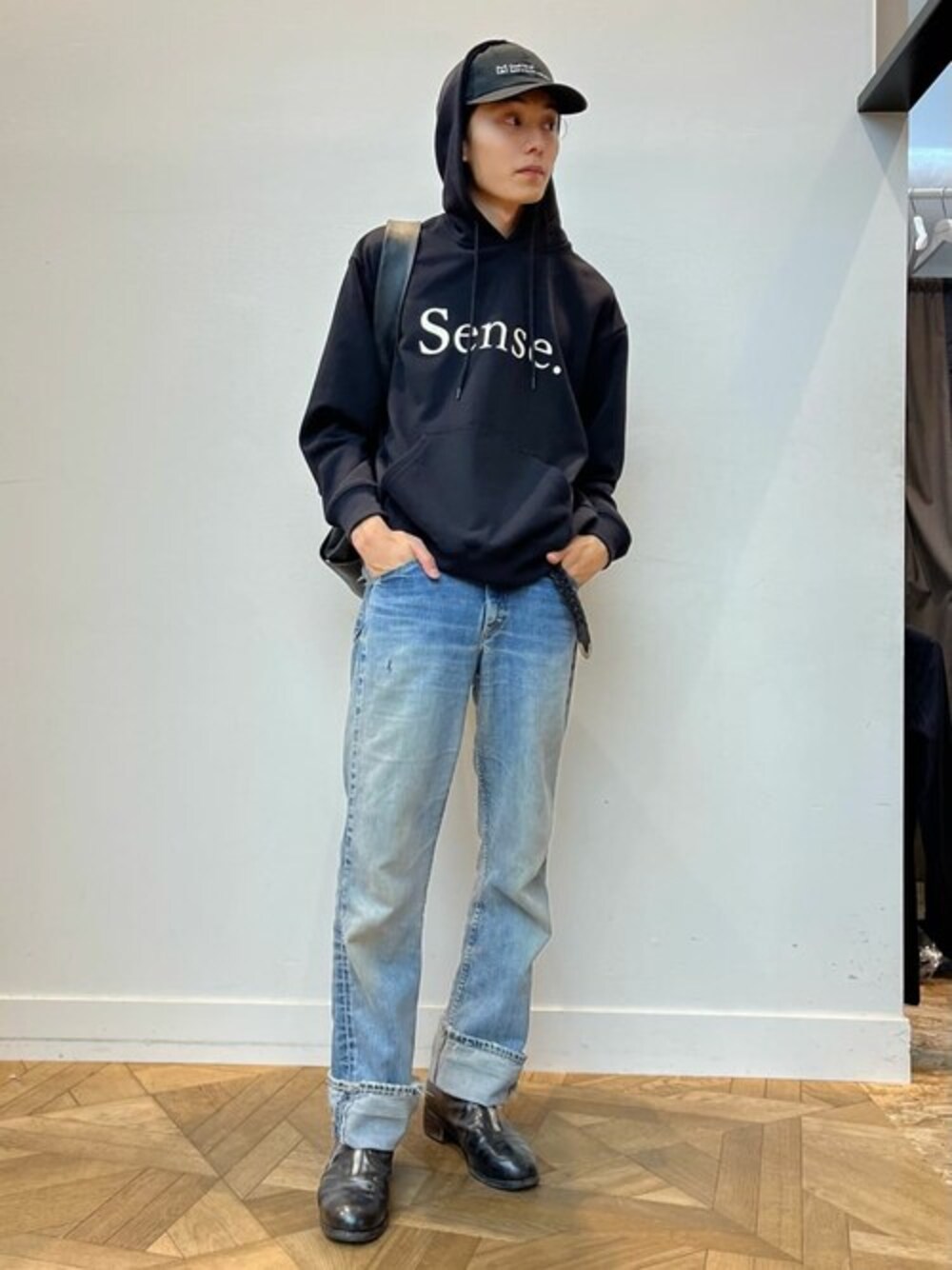 ブラック系のパーカー、ブラック系のショルダーバッグ、ブラック系のキャップを着用したメンズの秋コーディネートの1枚目の写真