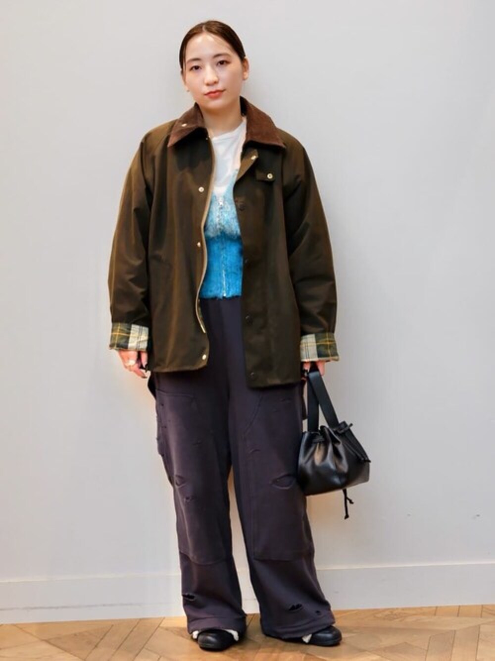 オレンジ系のカーディガン/ボレロ、グレー系のスウェットパンツ、グリーン系のステンカラーコートを着用したレディースの冬コーディネートの1枚目の写真