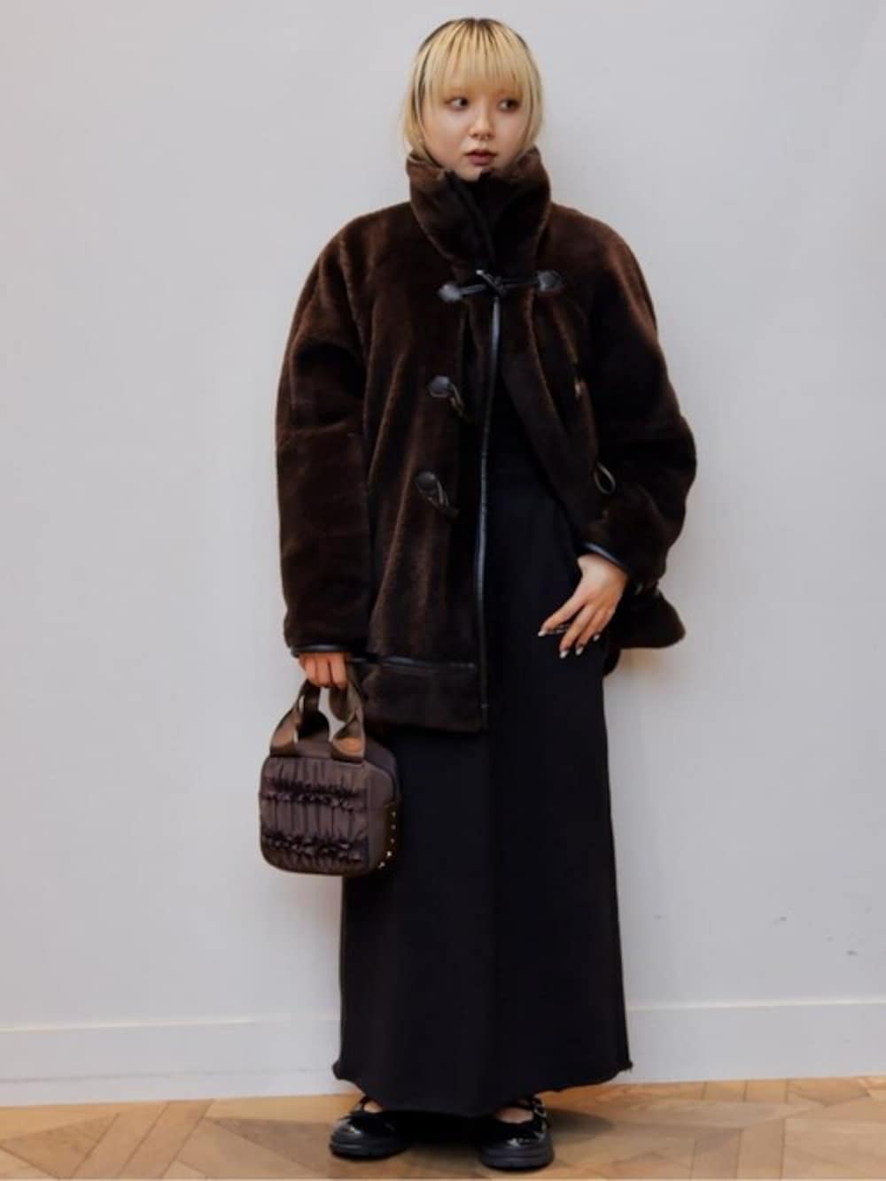 ブラック系のスカート、ブラウン系のダッフルコート、ブラック系のニット/セーターを着用したレディースの冬コーディネートの1枚目の写真