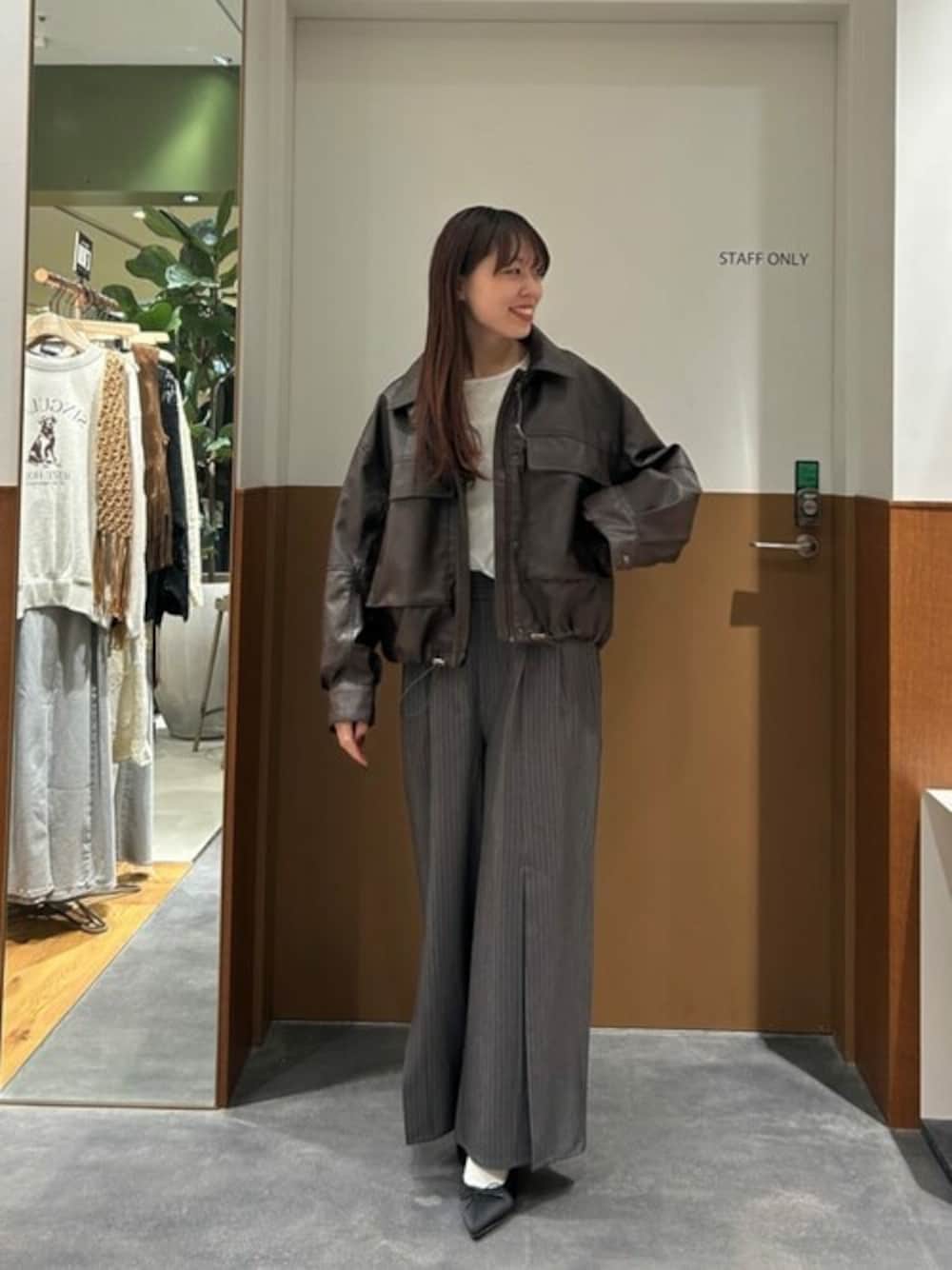 ブラウン系のブルゾン、グレー系のスラックス、ホワイト系のTシャツ/カットソーを着用したレディースの春コーディネートの1枚目の写真