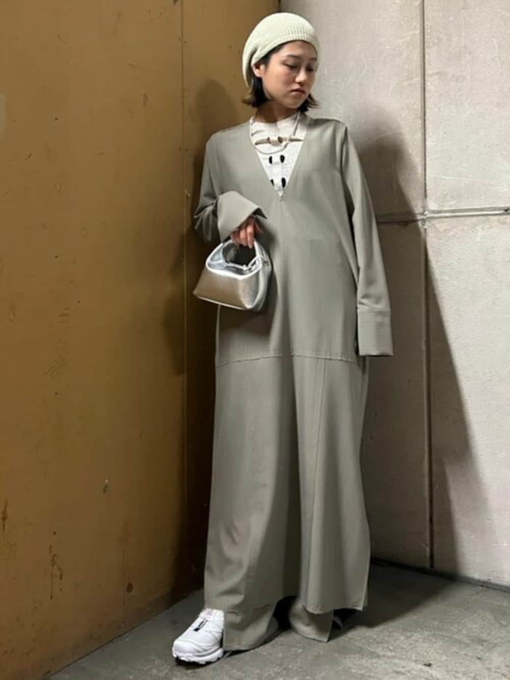 グレー系のスラックス、グレー系のワンピース、ホワイト系のニット/セーターを着用したレディースの春コーディネートの1枚目の写真