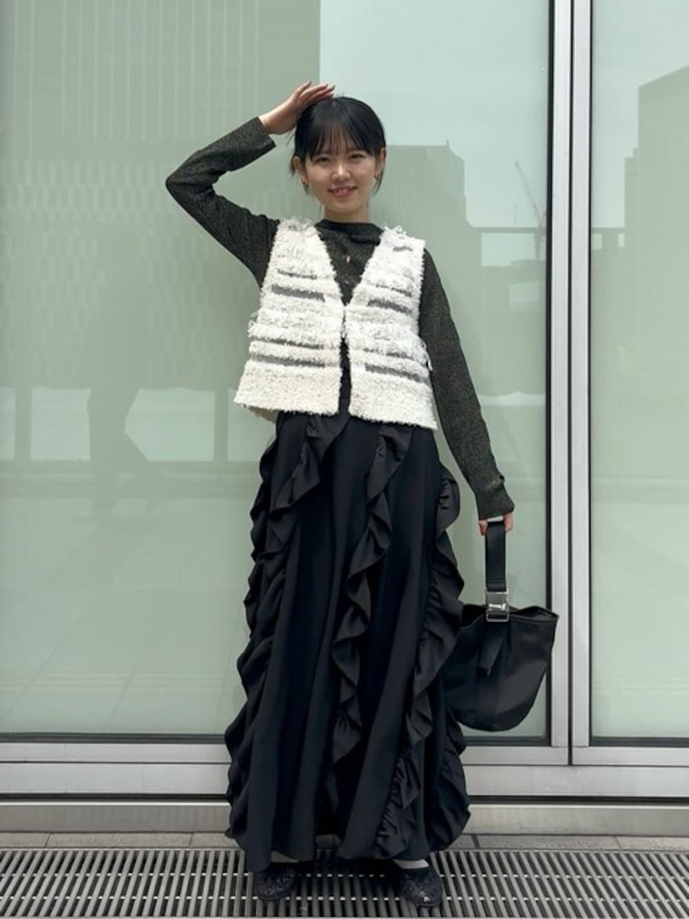 ホワイト系のベスト、ブラック系のその他シューズ、ブラック系のスカートを着用したレディースの春コーディネートの1枚目の写真