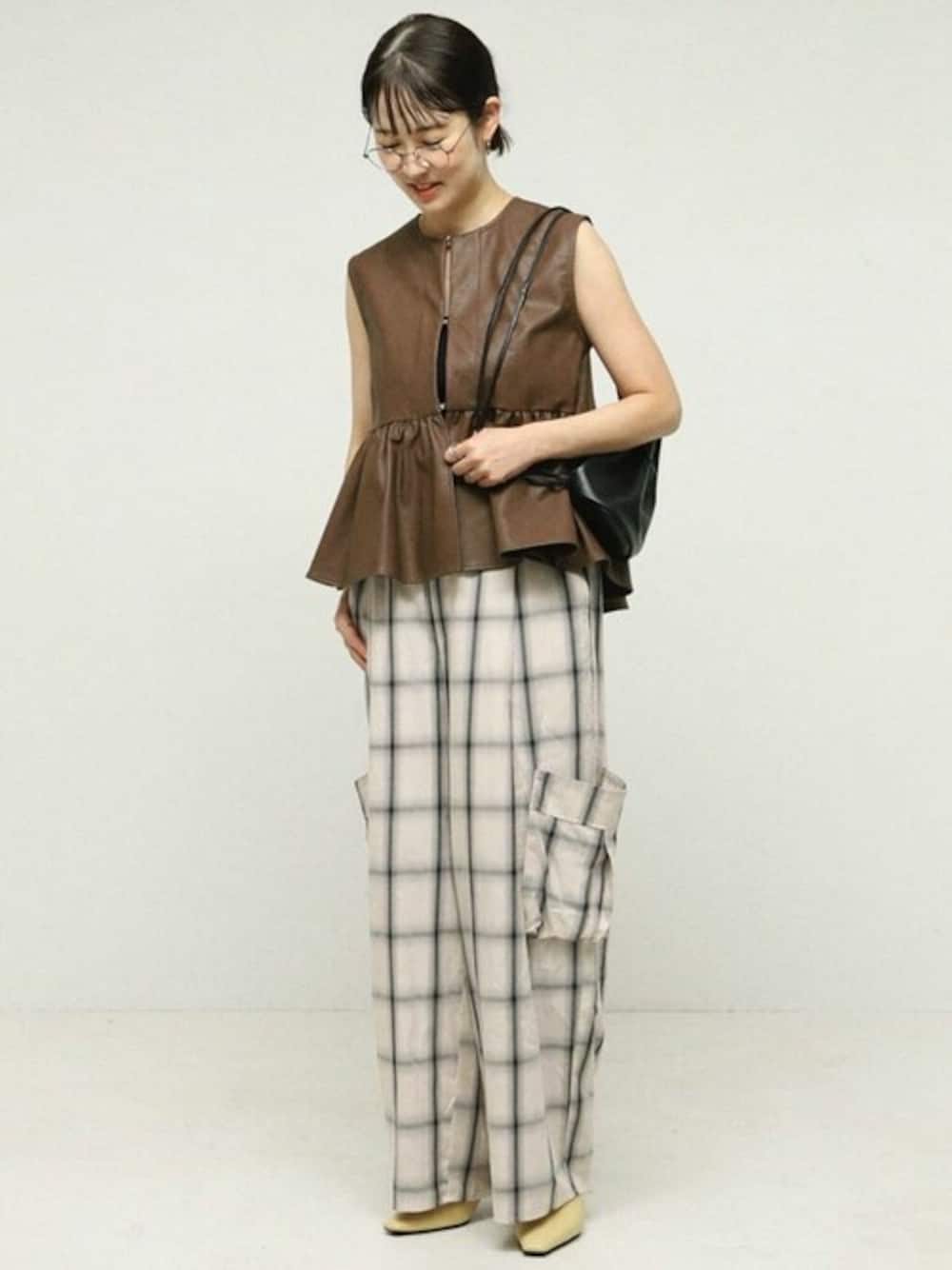 ブラウン系のベスト、ホワイト系のその他パンツ、ブラック系のショルダーバッグを着用したレディースの秋コーディネートの1枚目の写真