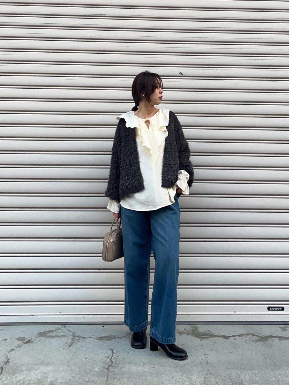 ブルー系のデニムパンツ、ホワイト系のシャツ/ブラウス、ベージュ系のボストンバッグを着用したレディースの秋コーディネートの1枚目の写真