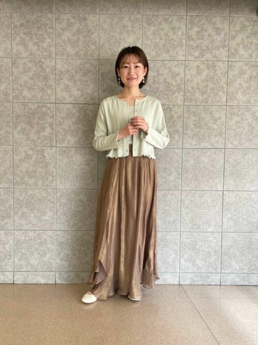 ブラウン系のスカート、グリーン系のTシャツ/カットソーを着用したレディースの春コーディネートの1枚目の写真