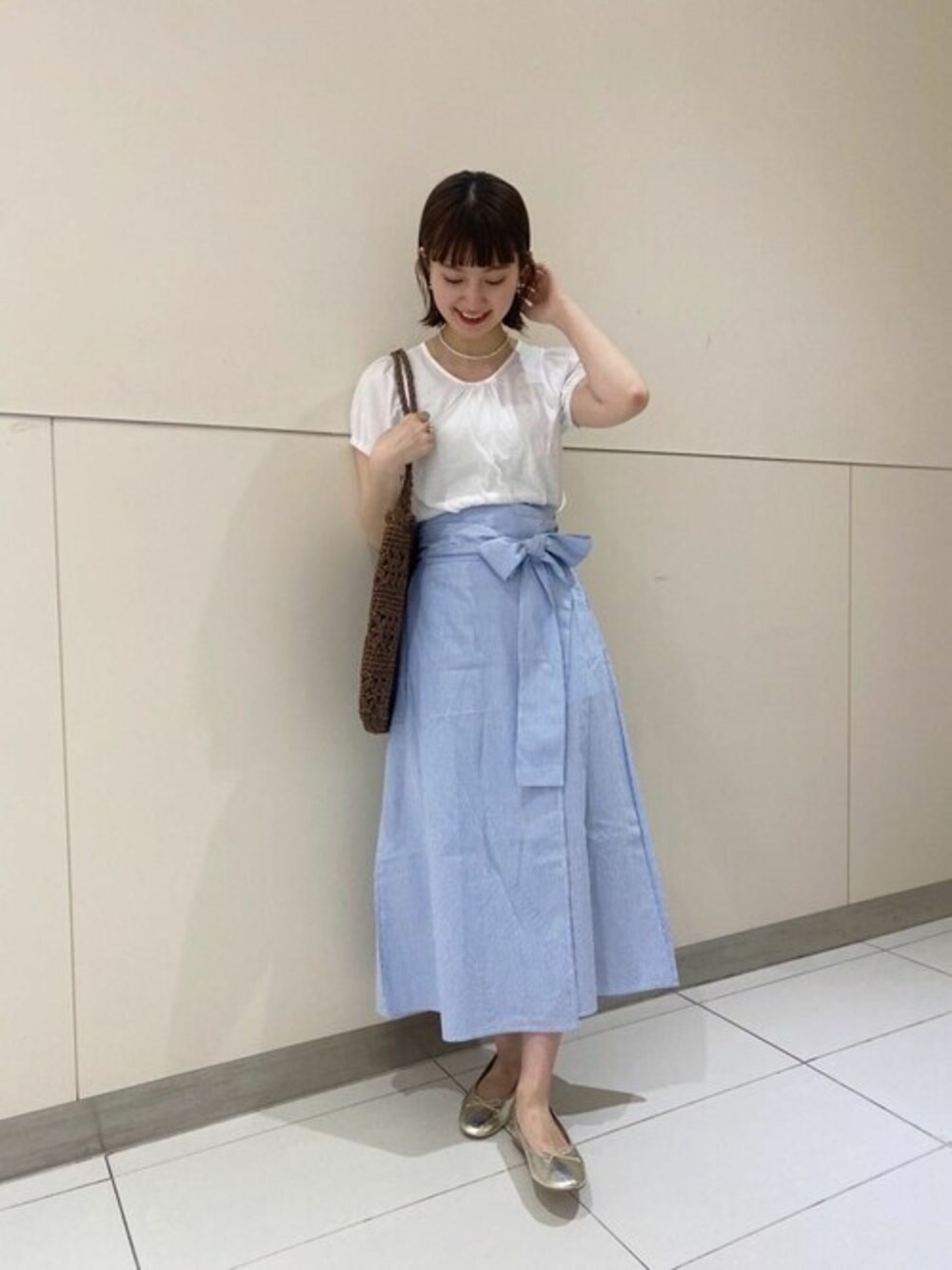 ホワイト系のTシャツ/カットソー、ブルー系のスカート、ブラウン系のかごバッグを着用したレディースの春コーディネートの1枚目の写真