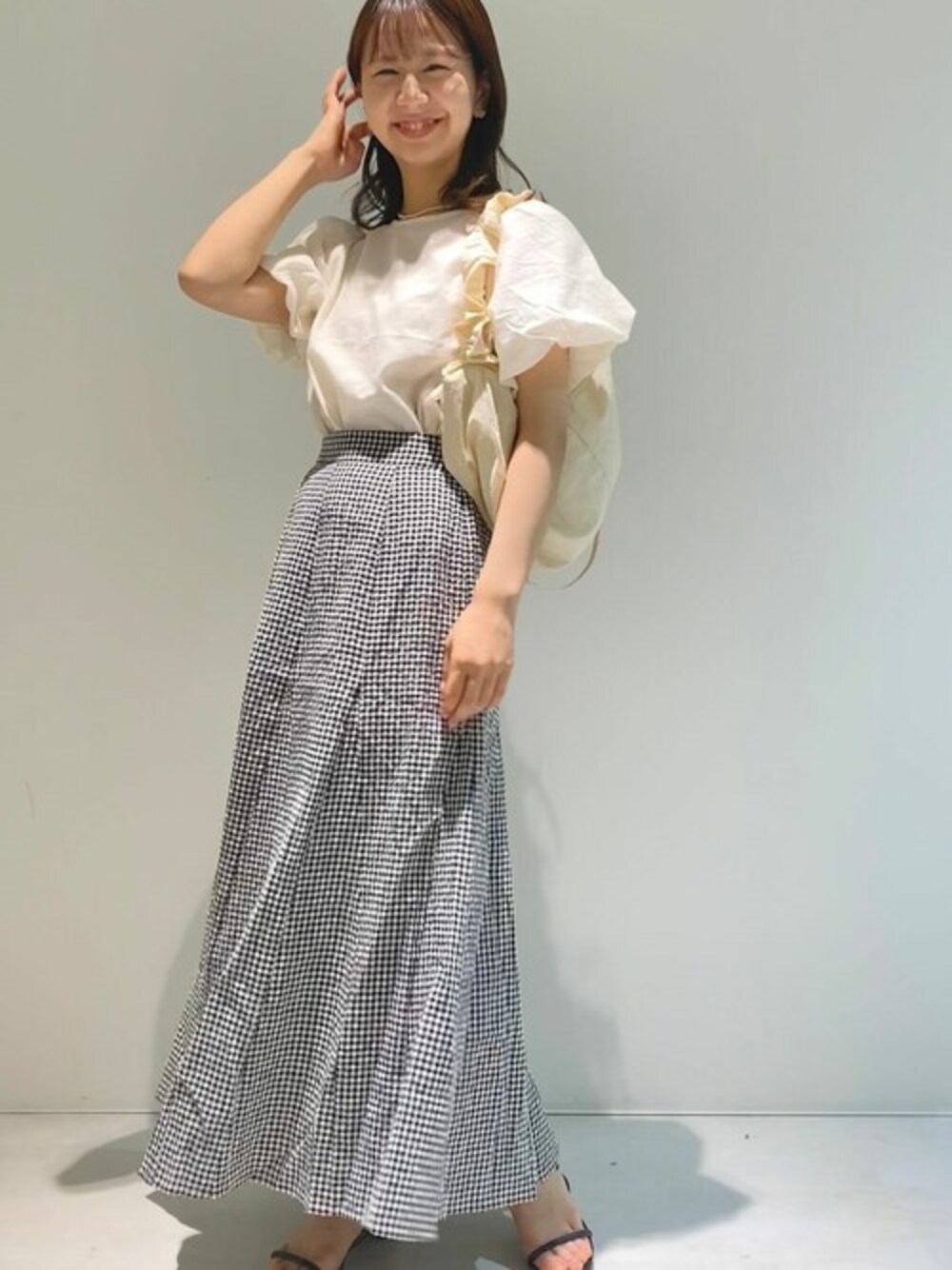 ホワイト系のシャツ/ブラウス、ブラック系のスカート、ホワイト系のショルダーバッグを着用したレディースの夏コーディネートの1枚目の写真