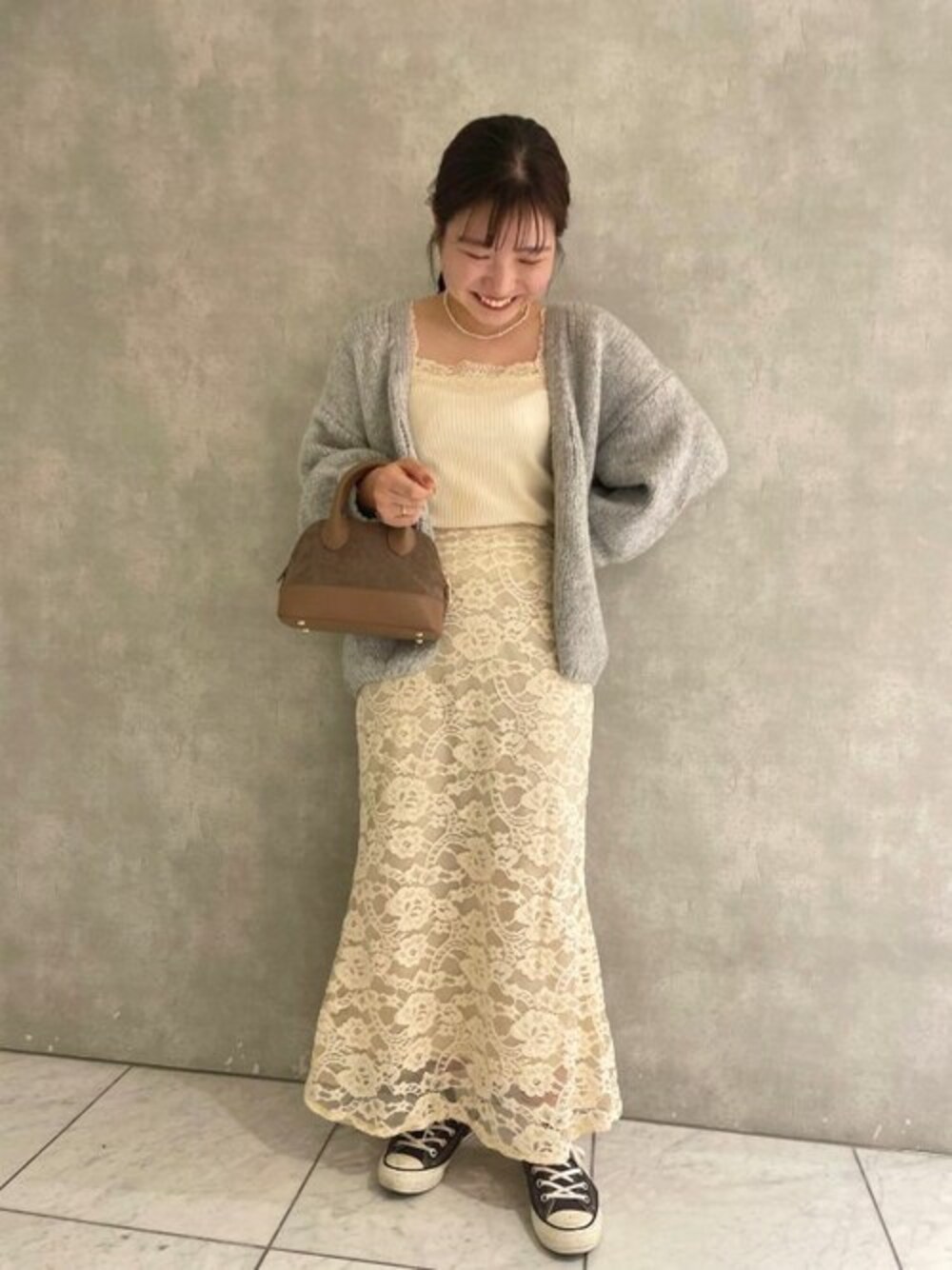グレー系のカーディガン/ボレロ、ベージュ系のショルダーバッグ、ホワイト系のスカートを着用したレディースの秋コーディネートの1枚目の写真