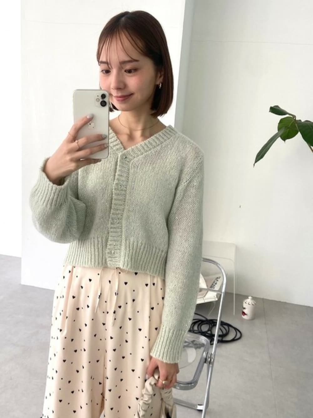 ホワイト系のその他パンツ、グリーン系のニット/セーター、ホワイト系のショルダーバッグを着用したレディースの冬コーディネートの1枚目の写真