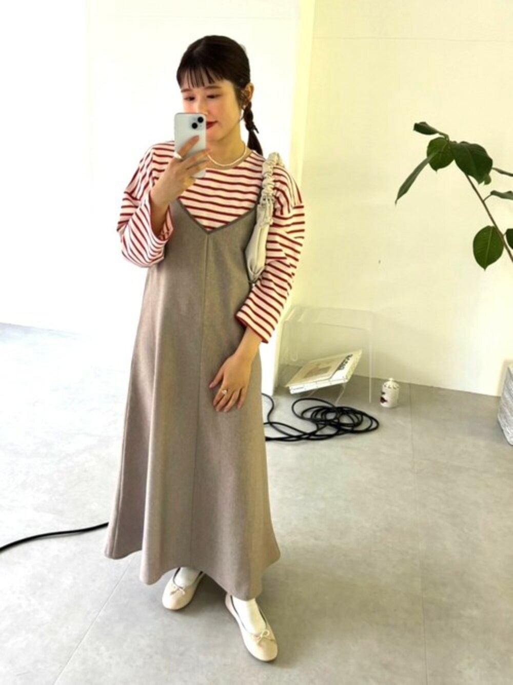 ベージュ系のワンピース、レッド系のTシャツ/カットソー、ホワイト系のショルダーバッグを着用したレディースの冬コーディネートの1枚目の写真