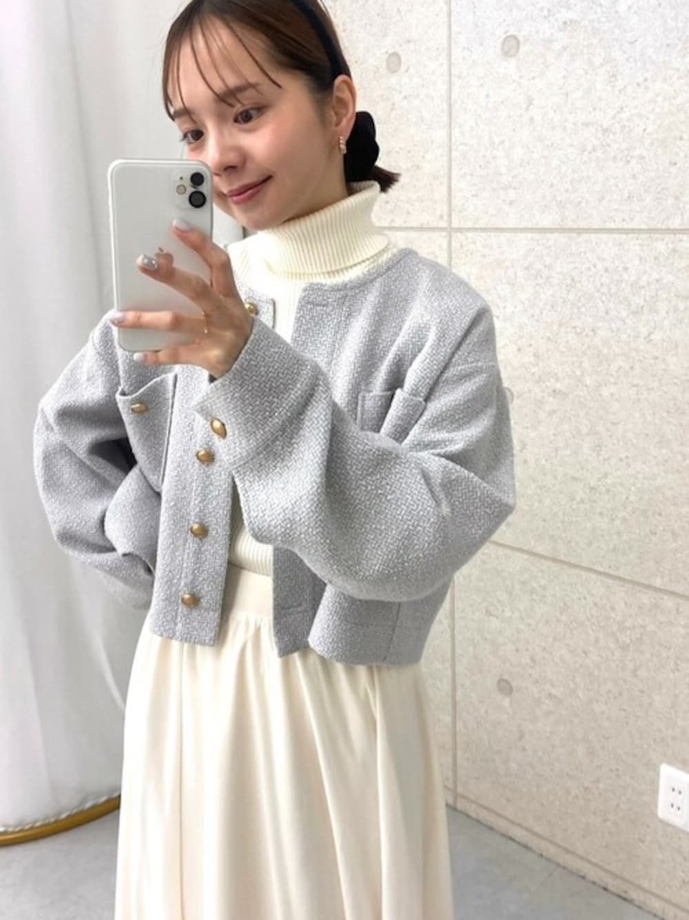 グレー系のノーカラージャケット、ホワイト系のスカート、ホワイト系のニット/セーターを着用したレディースの冬コーディネートの1枚目の写真