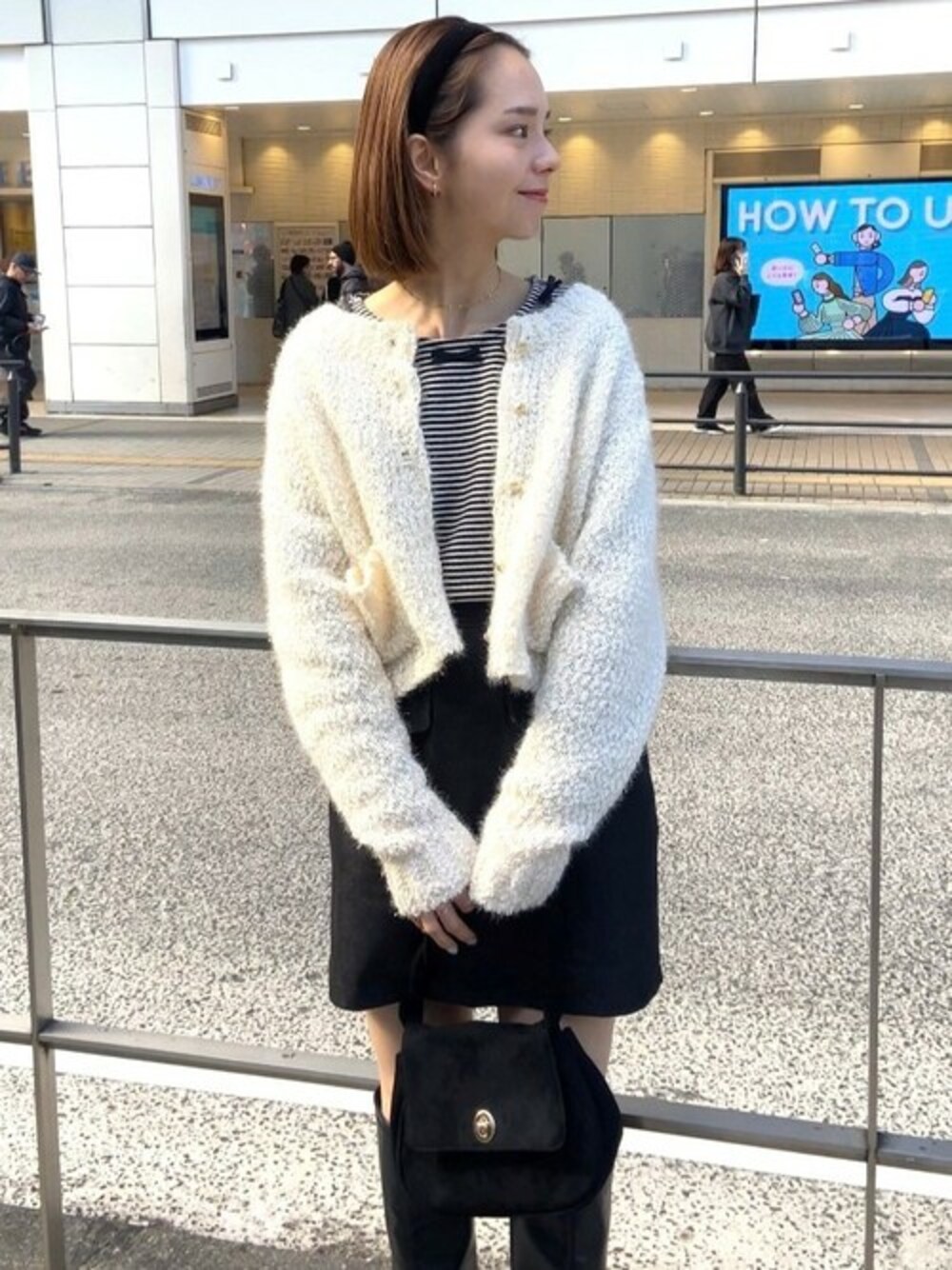 ブラック系のTシャツ/カットソー、ホワイト系のニット/セーター、ブラック系のデニムスカートを着用したレディースの冬コーディネートの1枚目の写真