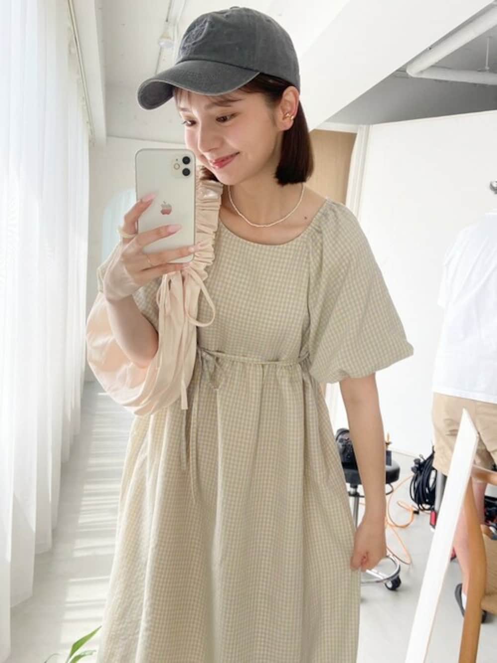 イエロー系のワンピース、ホワイト系のショルダーバッグ、ブラック系のキャップを着用したレディースの夏コーディネートの1枚目の写真