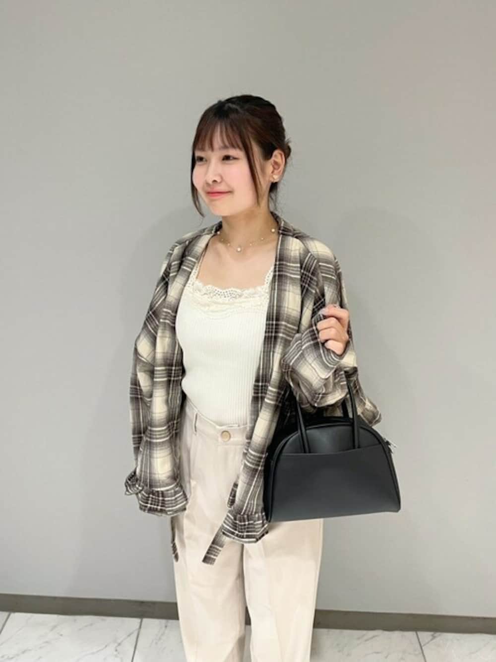 ベージュ系のノーカラージャケット、ホワイト系のキャミソール、ブラック系のハンドバッグを着用したレディースの秋コーディネートの1枚目の写真