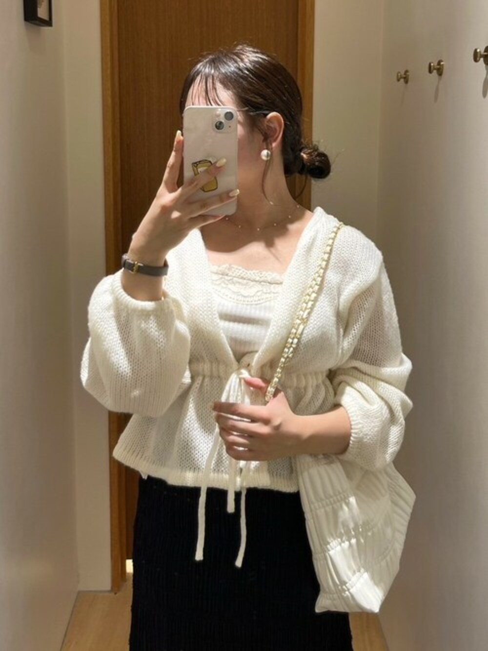 ホワイト系のニット/セーター、ホワイト系のキャミソール、ホワイト系のショルダーバッグを着用したレディースの秋コーディネートの1枚目の写真