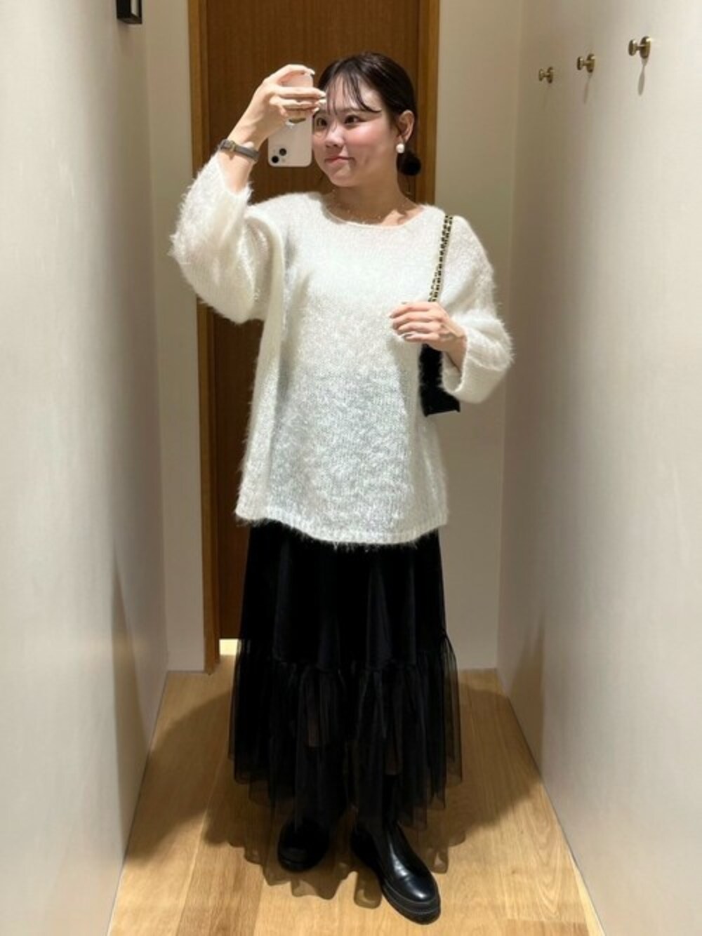 ホワイト系のニット/セーター、ブラック系のショルダーバッグ、ブラック系のスカートを着用したレディースの秋コーディネートの1枚目の写真