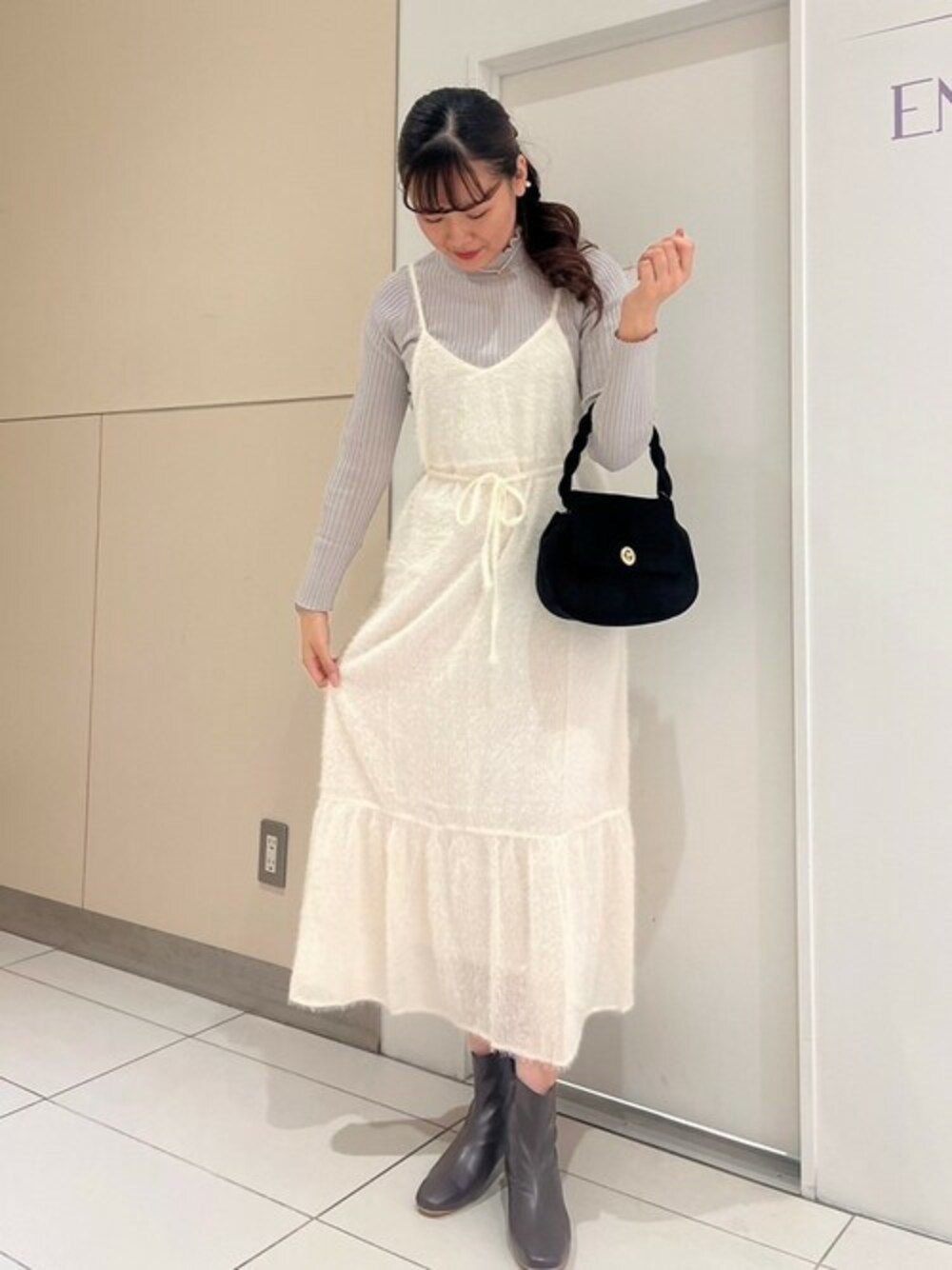 ホワイト系のワンピース、グレー系のニット/セーター、ブラック系のショルダーバッグを着用したレディースの秋コーディネートの1枚目の写真