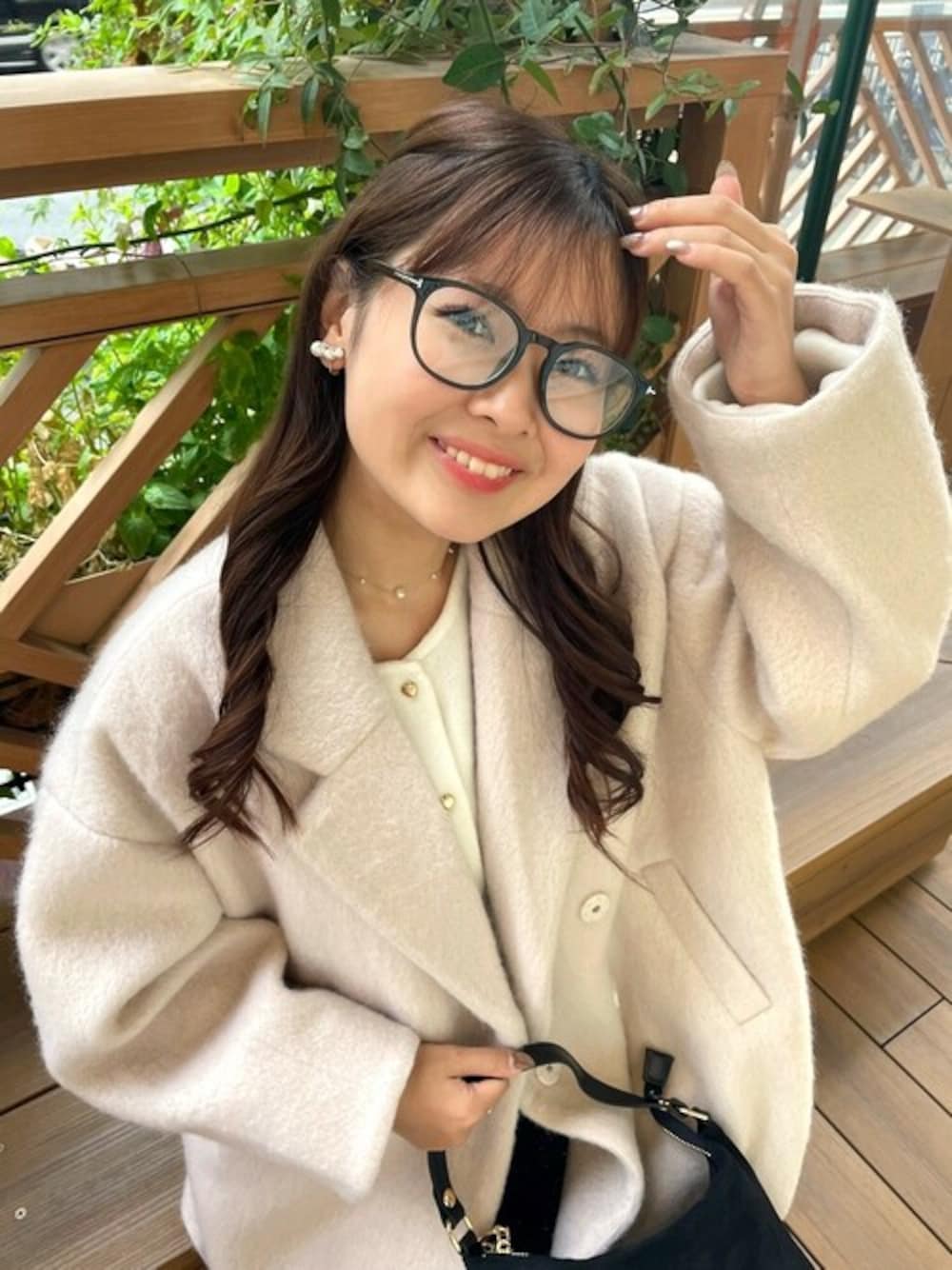 ブラック系のショルダーバッグ、ベージュ系のチェスターコート、ホワイト系のカーディガン/ボレロを着用したレディースの秋コーディネートの1枚目の写真