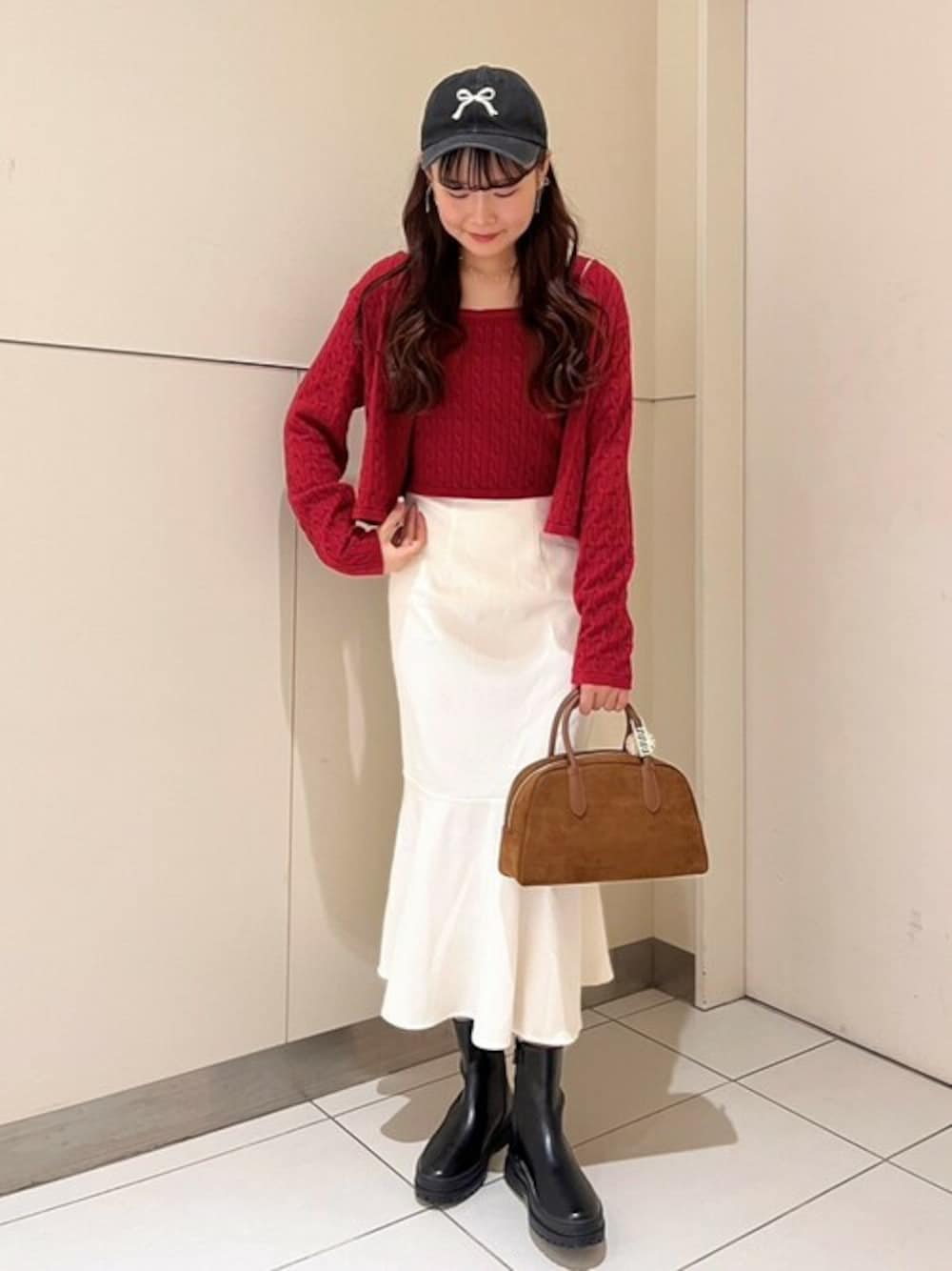 ブラウン系のハンドバッグ、レッド系のニット/セーター、ホワイト系のスカートを着用したレディースの秋コーディネートの1枚目の写真
