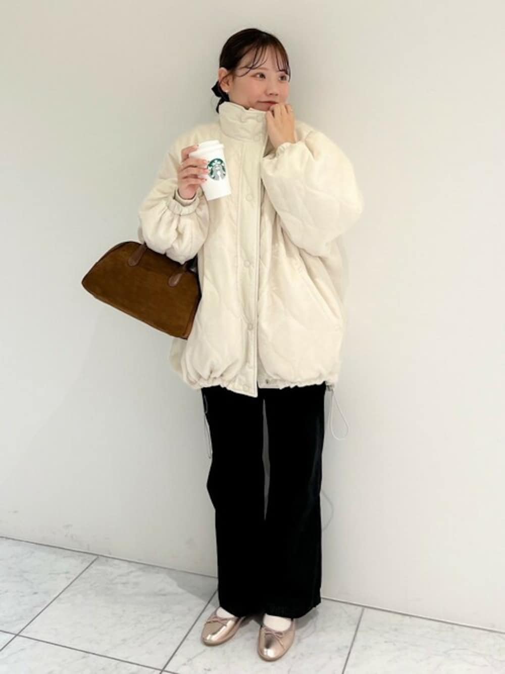 ホワイト系のナイロンジャケット、ブラウン系のハンドバッグ、ブラック系のデニムパンツを着用したレディースの秋コーディネートの1枚目の写真