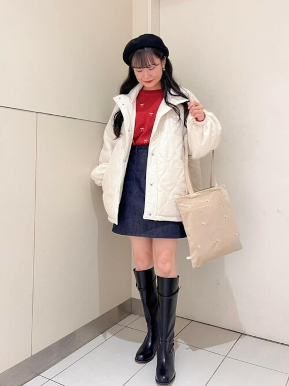 ホワイト系のナイロンジャケット、レッド系のニット/セーター、ブルー系のデニムスカートを着用したレディースの冬コーディネートの1枚目の写真